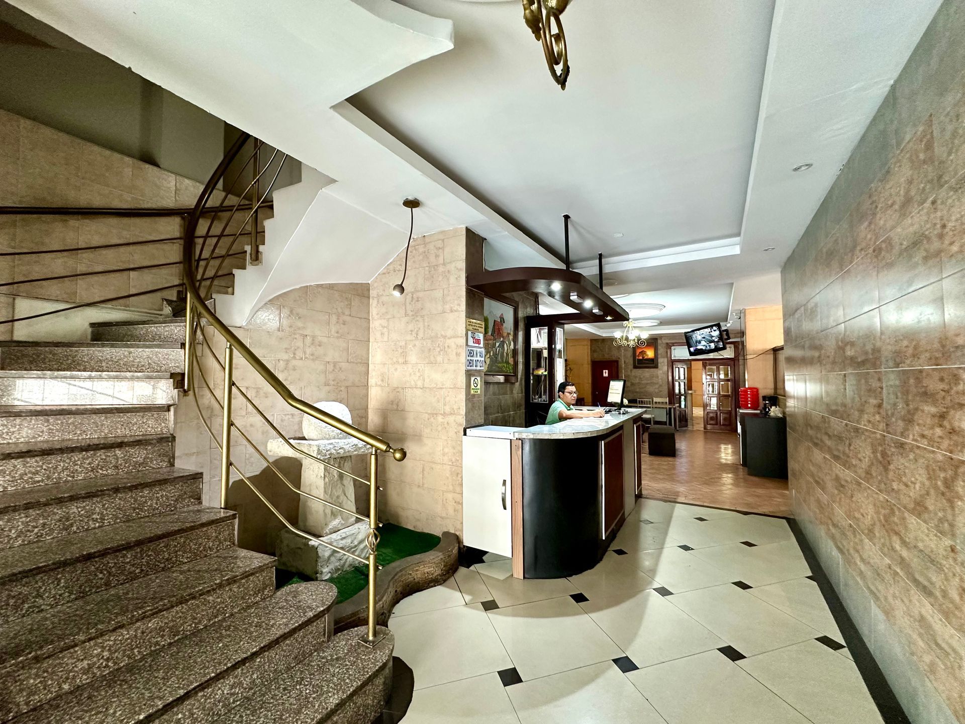 Un vestíbulo de hotel con escaleras y un mostrador de recepción.