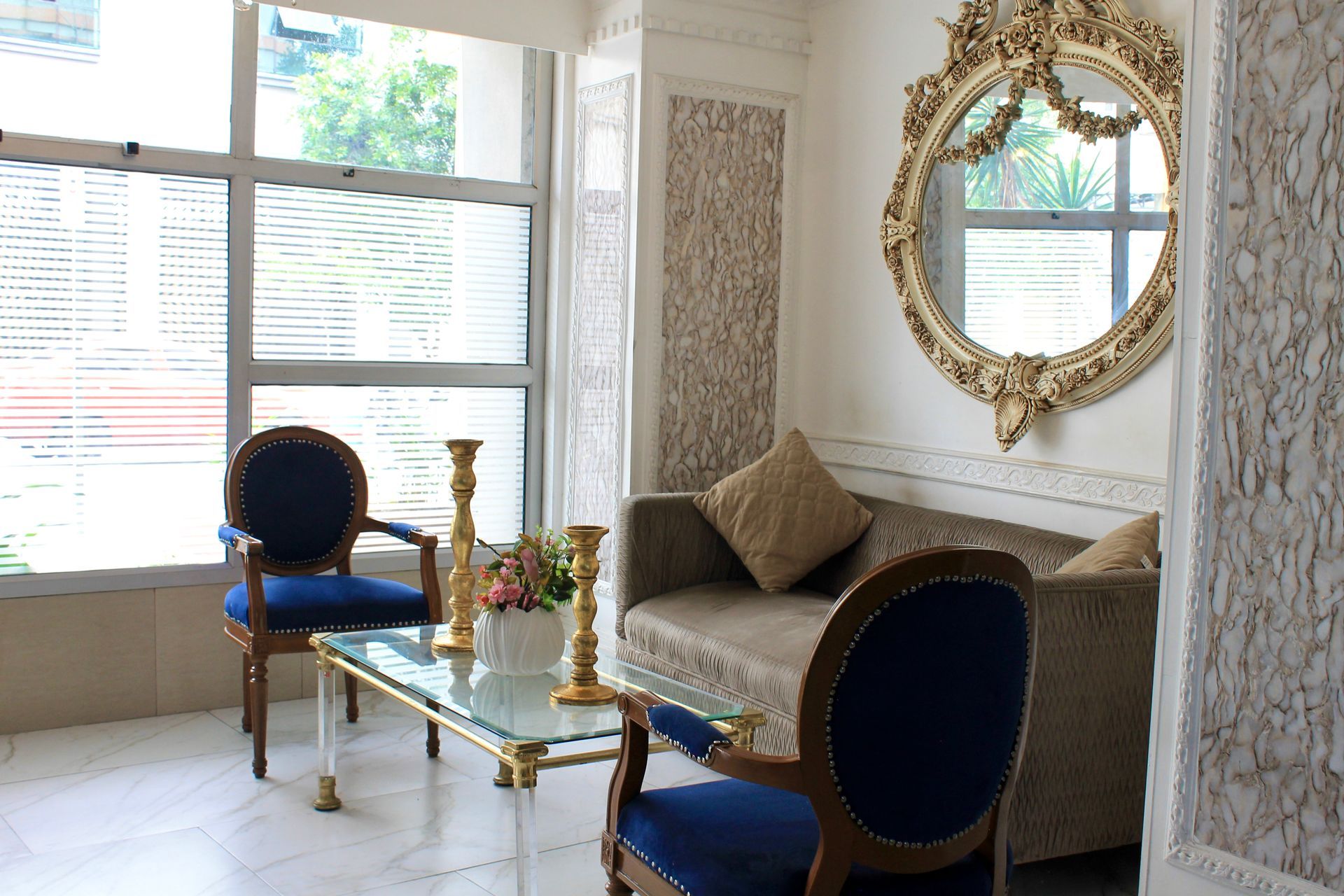 Una sala de estar con un sofá, sillas, una mesa y un espejo.