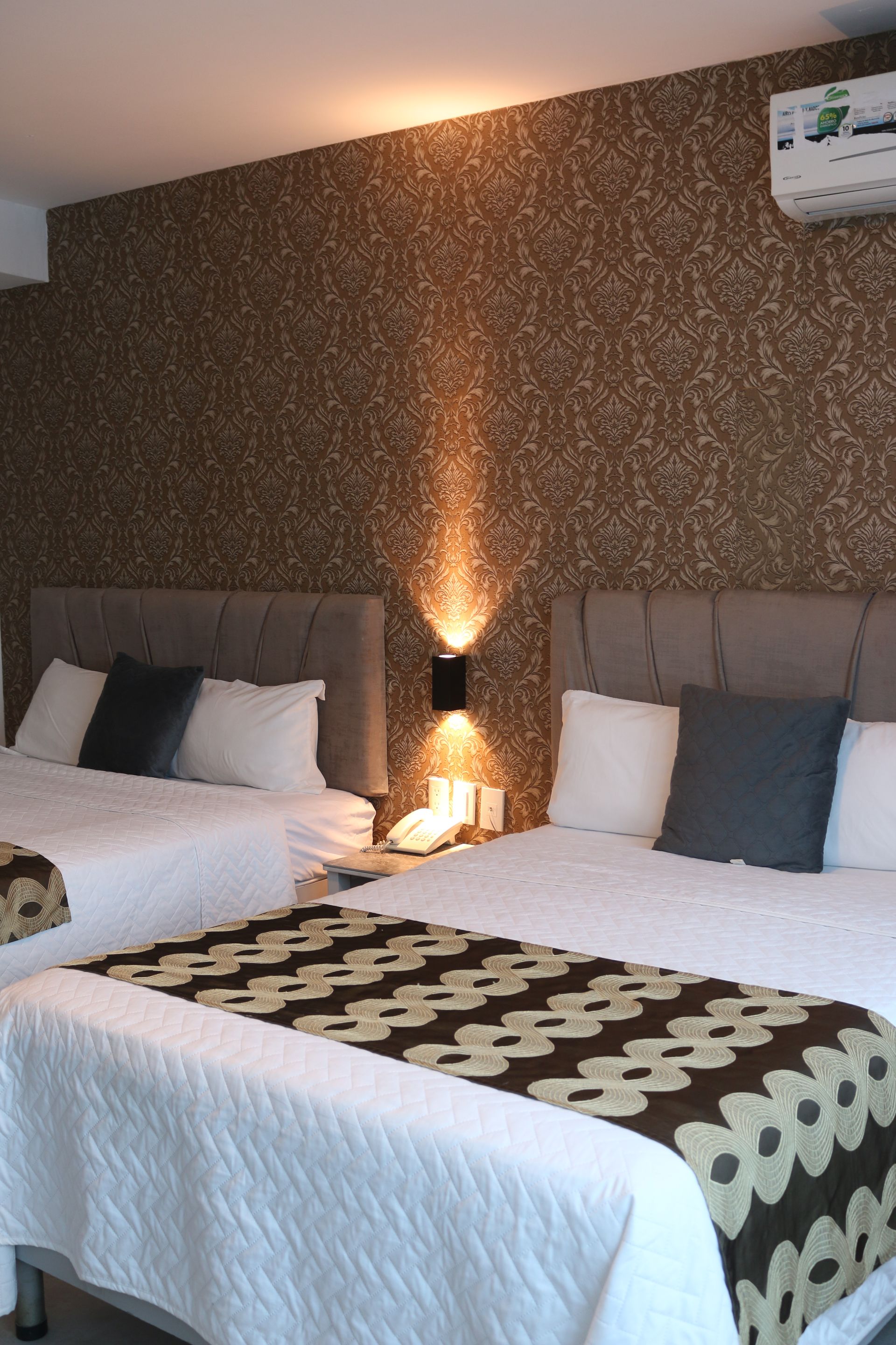 Una habitación de hotel con dos camas y aire acondicionado.