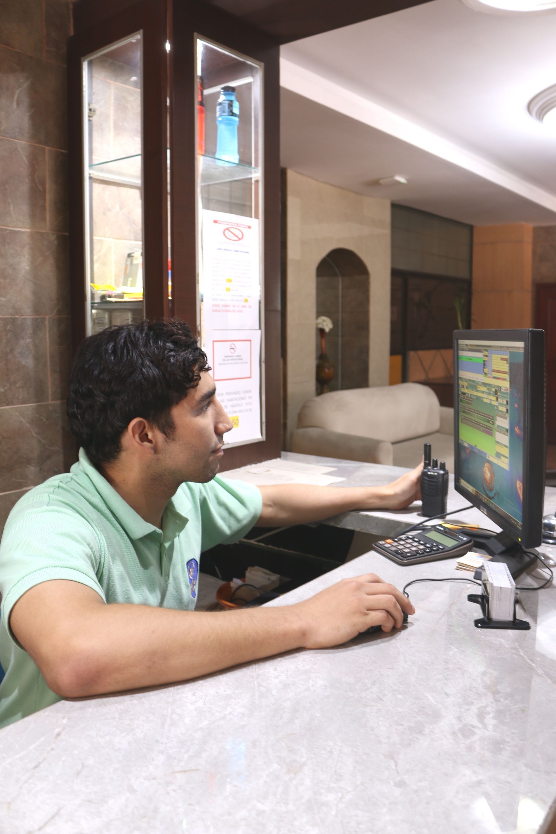 Un hombre con una camisa verde está mirando una pantalla de computadora.