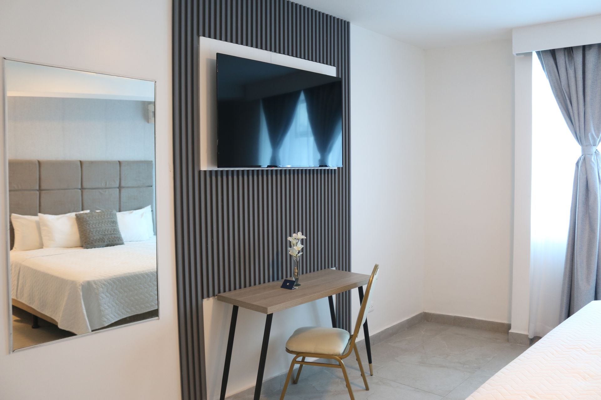 Una habitación de hotel con escritorio, silla, televisión y espejo.