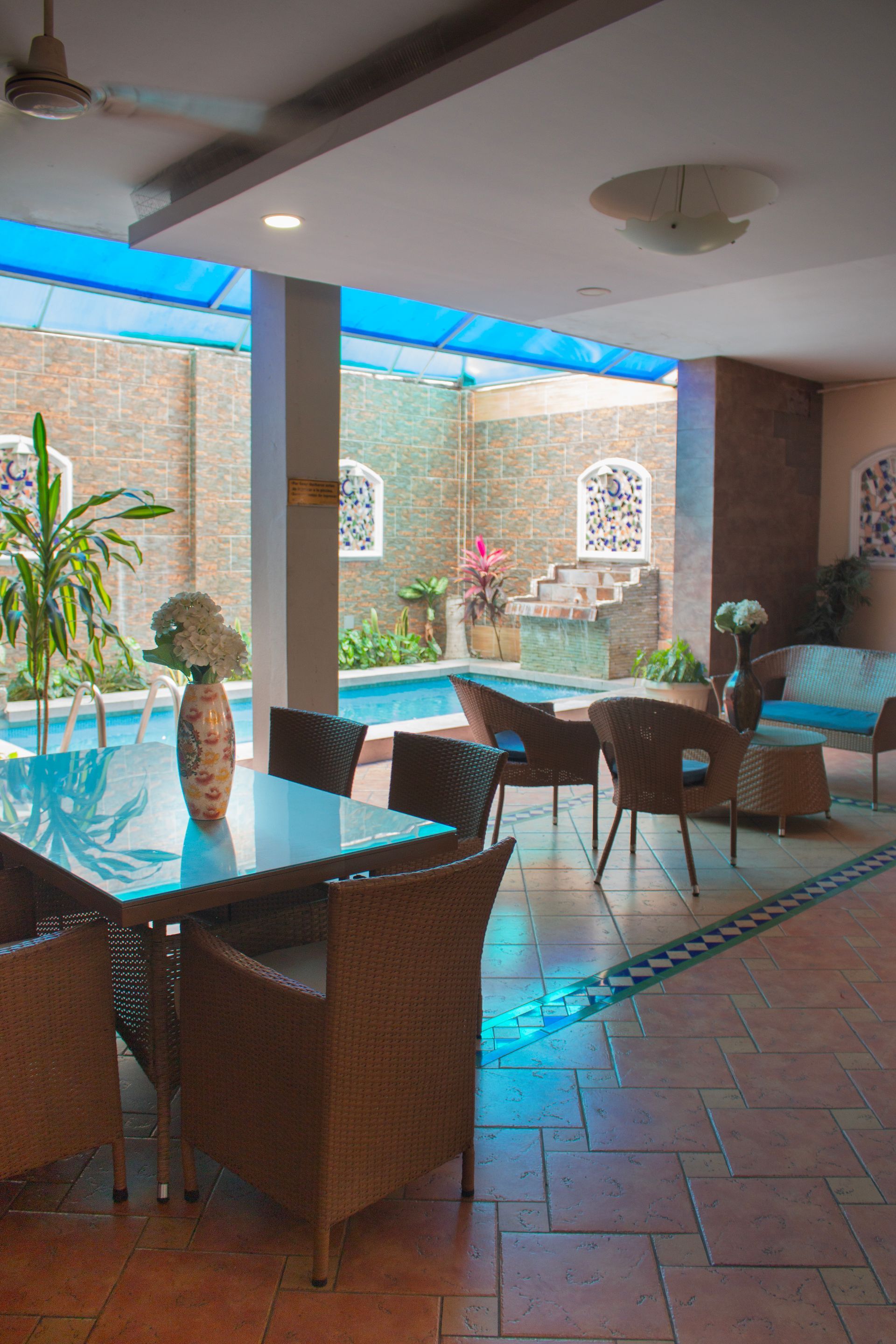 Una habitación con una mesa y sillas frente a una piscina.