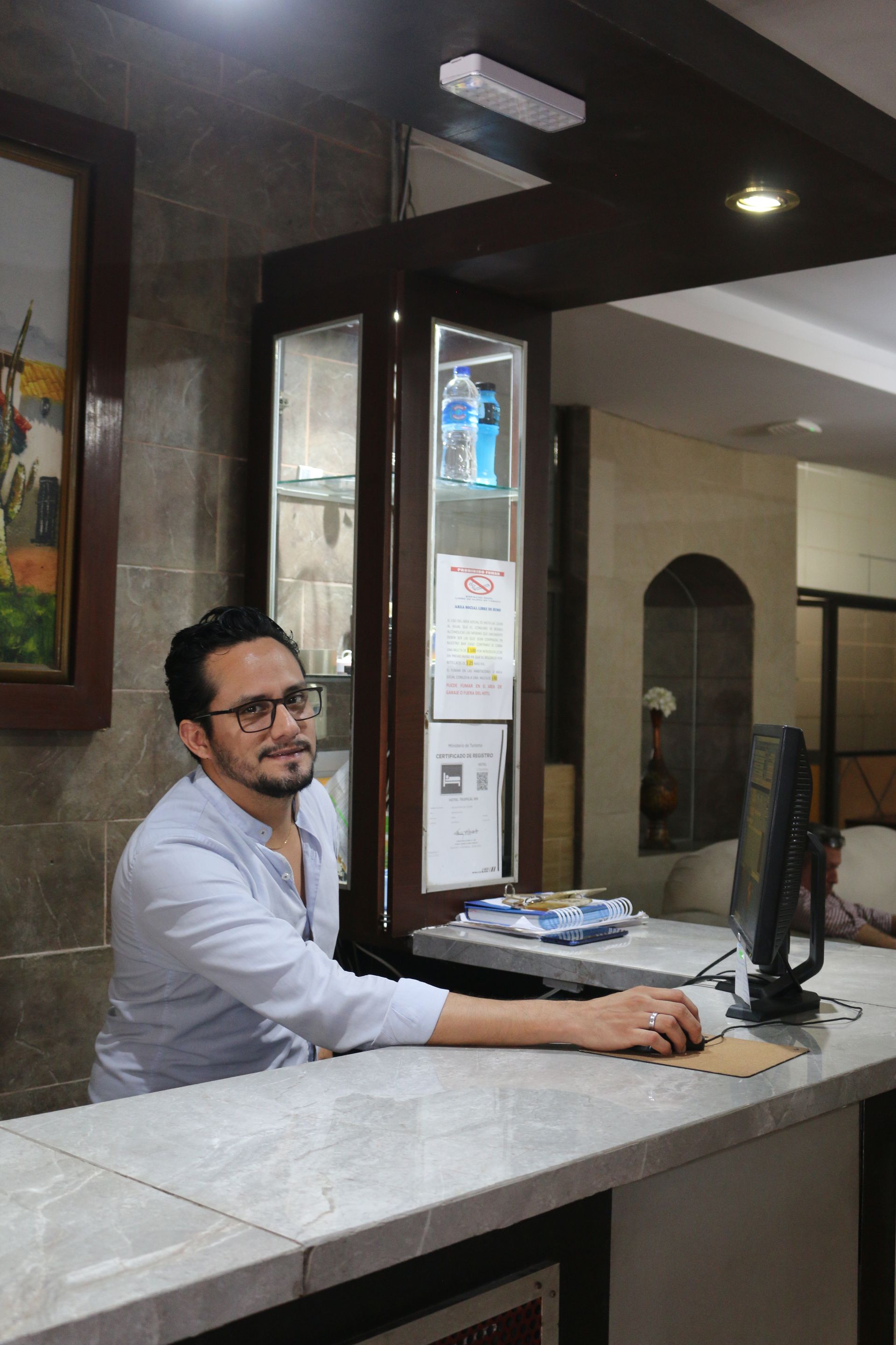 Un hombre está sentado en un mostrador frente a una computadora.