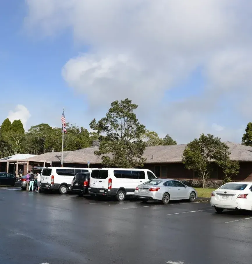Una fila de coches están aparcados delante de un edificio.