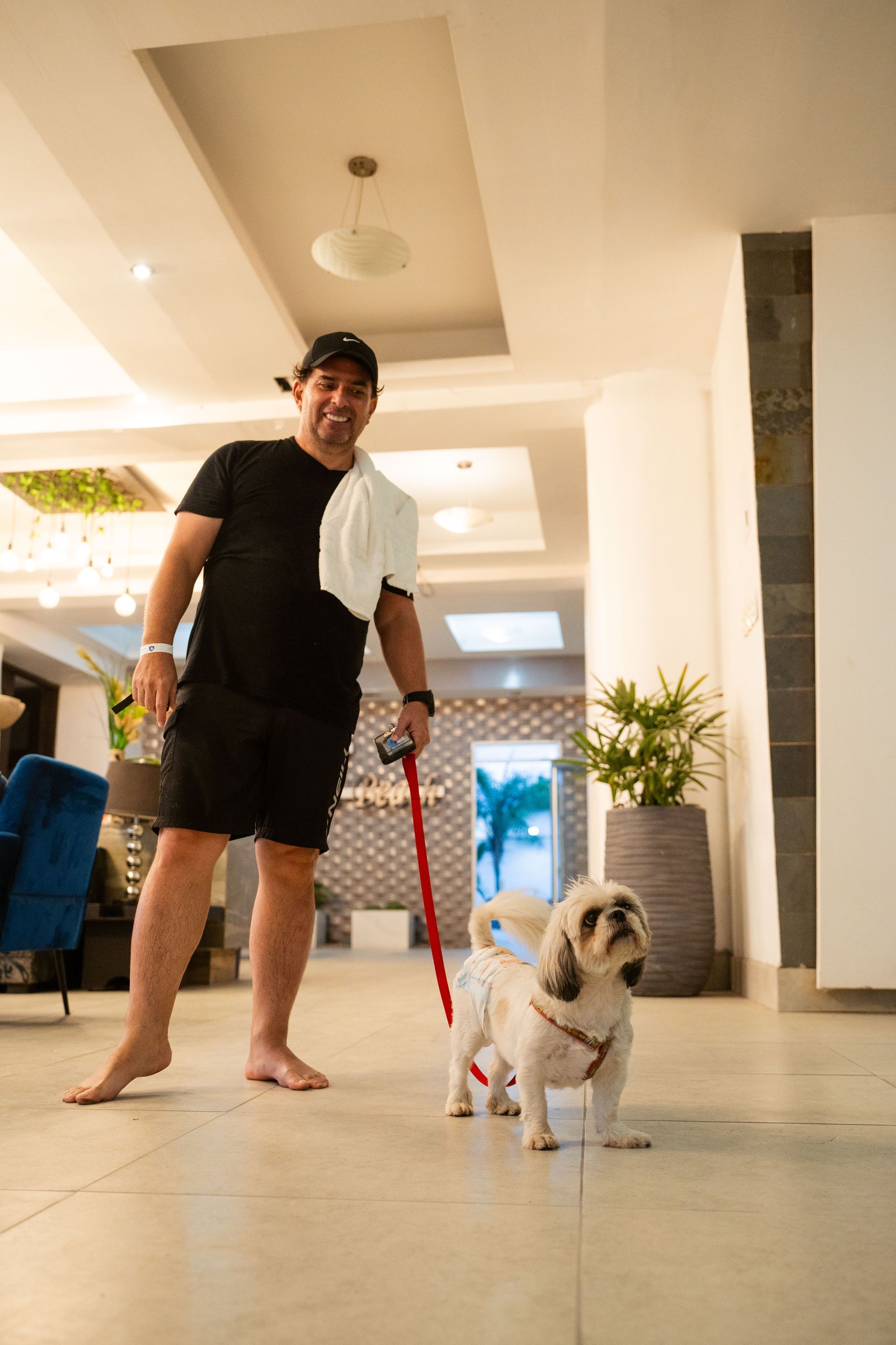 Un hombre pasea a un perro pequeño con una correa.