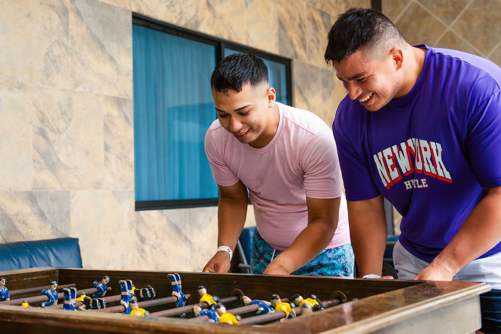 Dos hombres están jugando una partida de futbolín en una mesa.