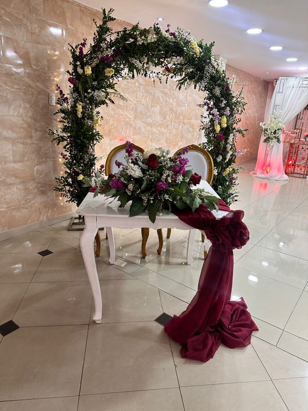 Una mesa y sillas están decoradas con flores y un arco floral.