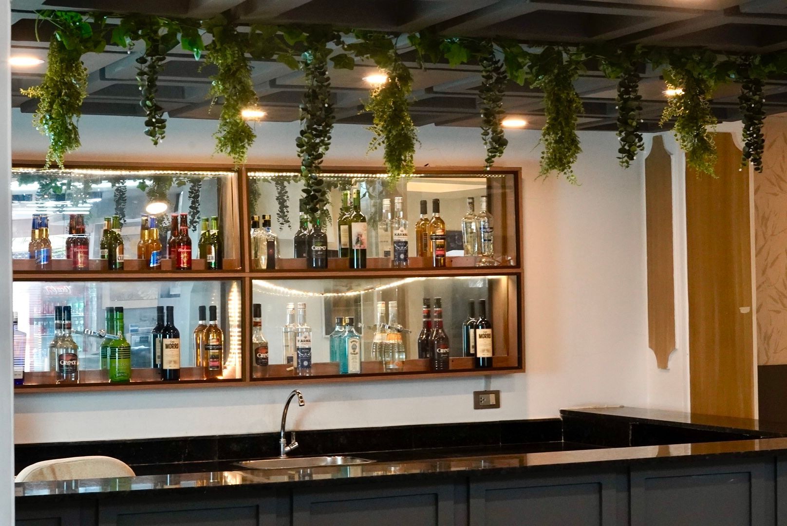 Un bar con muchas botellas en los estantes y un fregadero.