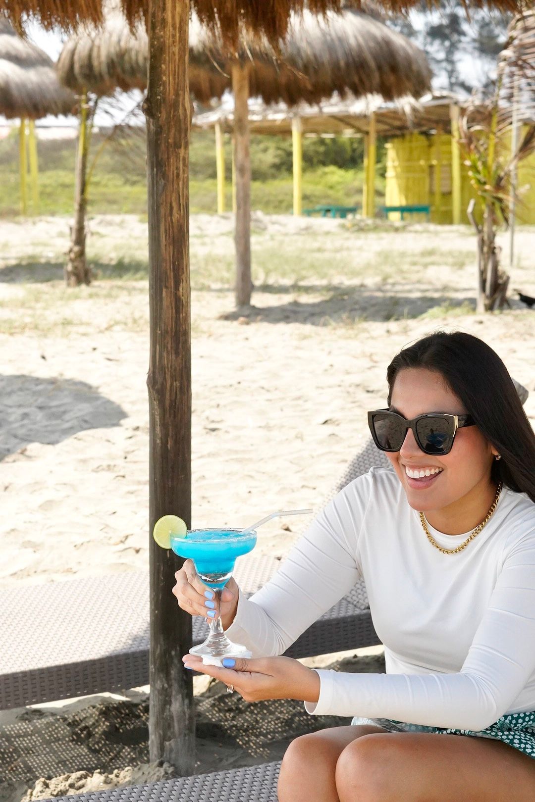 Una mujer está sentada en la playa sosteniendo una margarita azul.