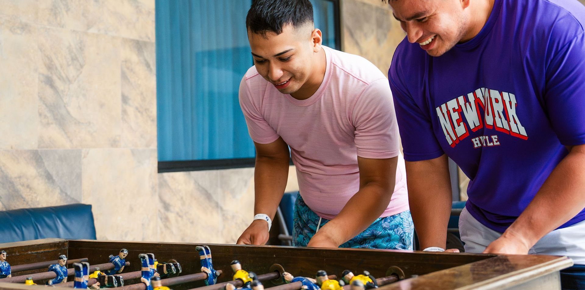 Dos hombres están jugando una partida de futbolín en una mesa.