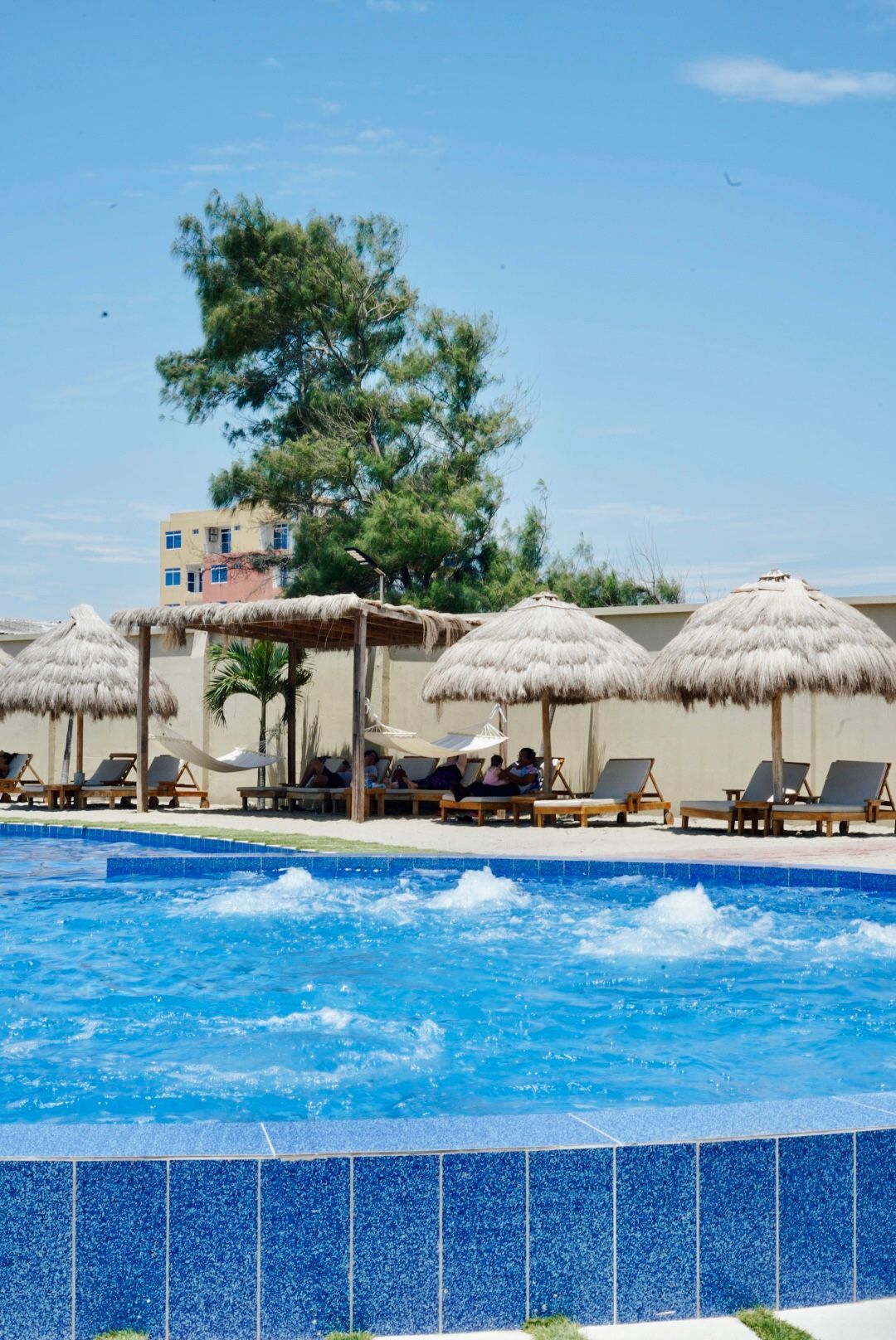 Una piscina con sombrillas y sillas alrededor.