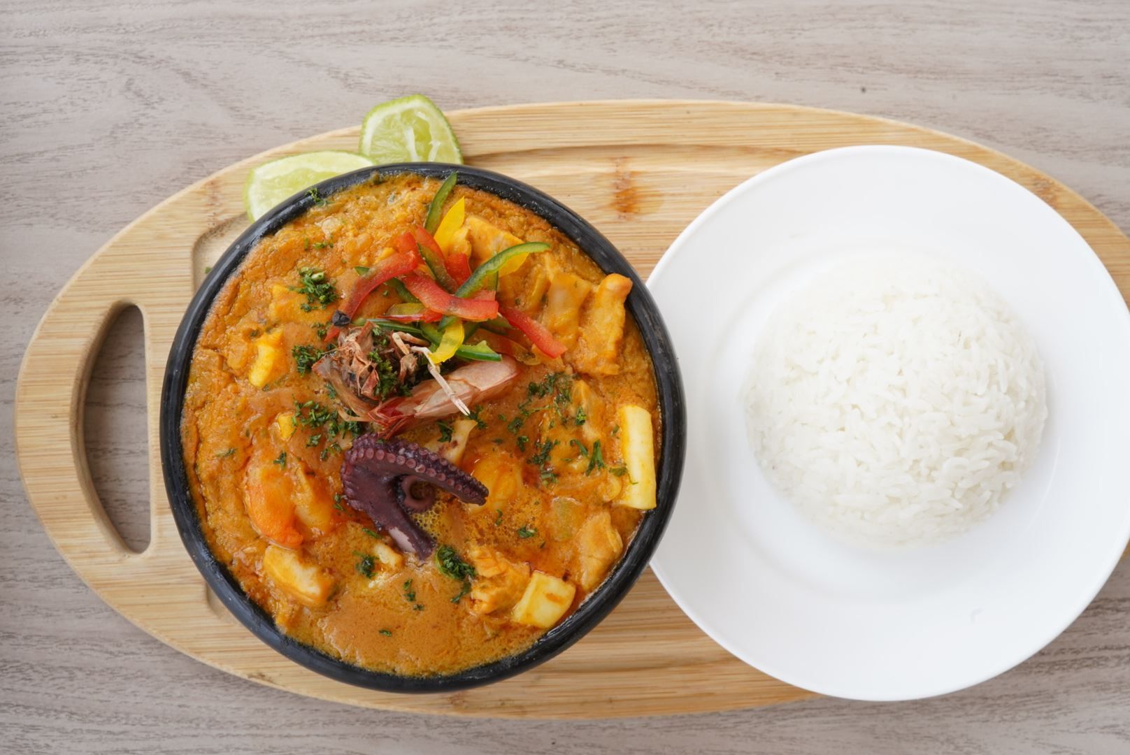 Un tazón de curry y arroz en una tabla de cortar de madera.