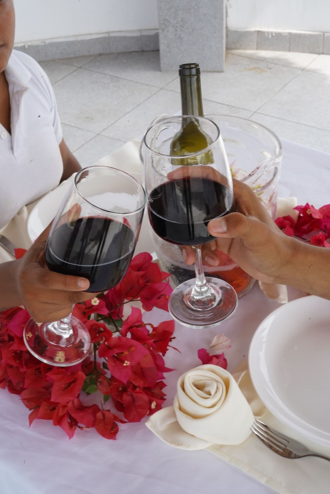 Dos personas brindando con copas de vino y una botella de vino.