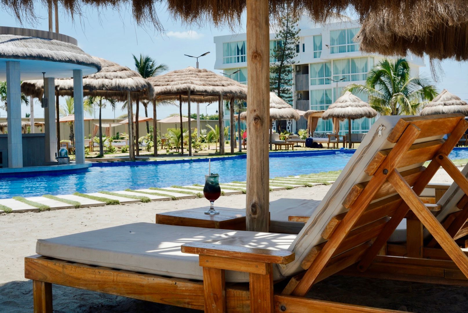Una piscina con sillas y sombrillas frente a ella.