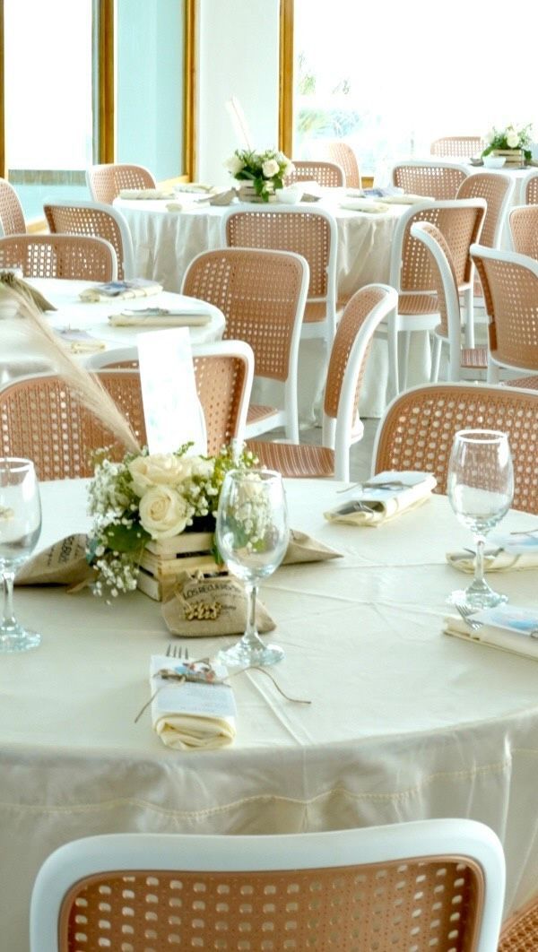Un comedor con mesas y sillas preparadas para una recepción de boda.