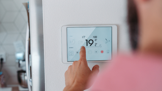 A person is using a tablet to control a thermostat.