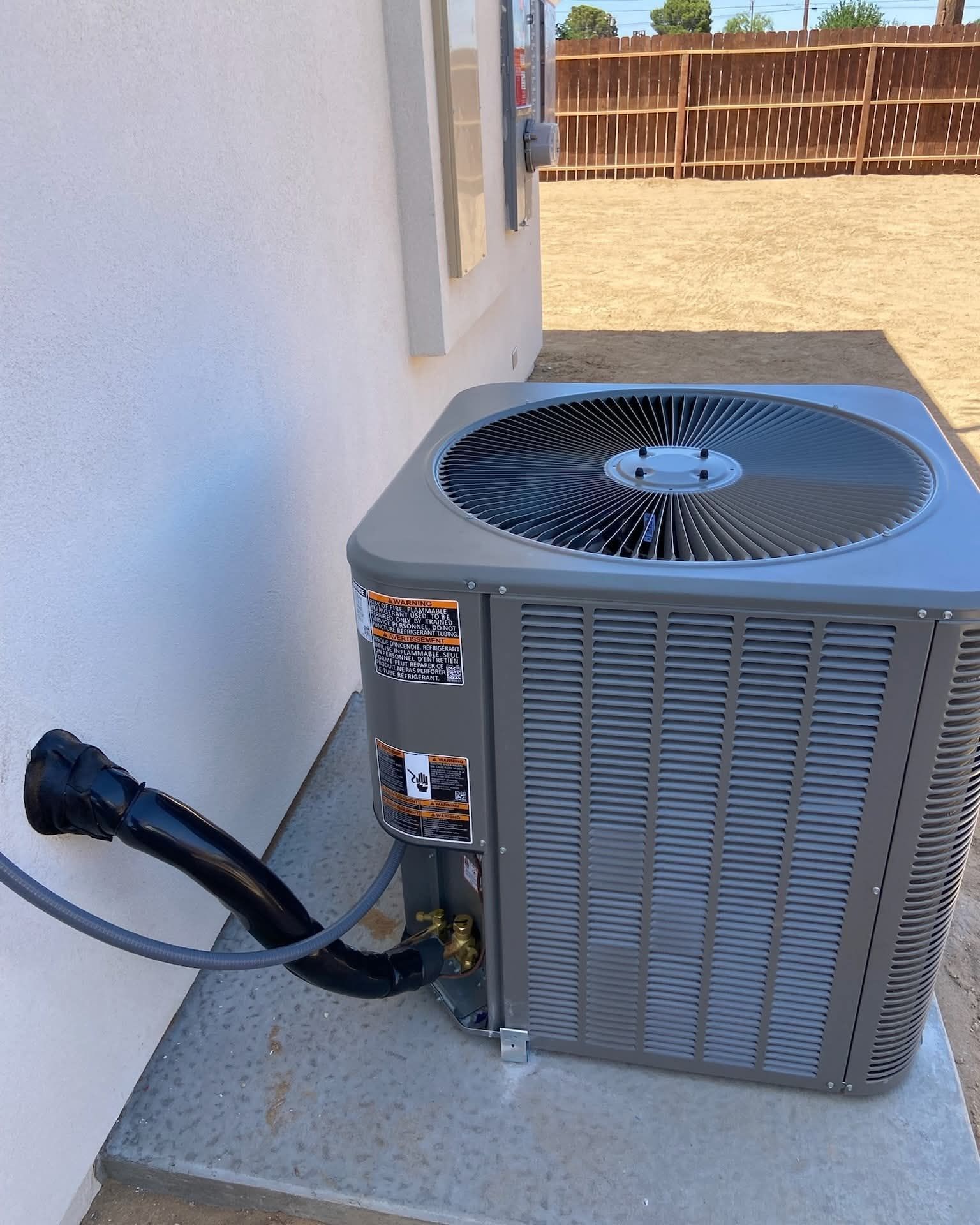 A gray air conditioner is attached to the side of a building