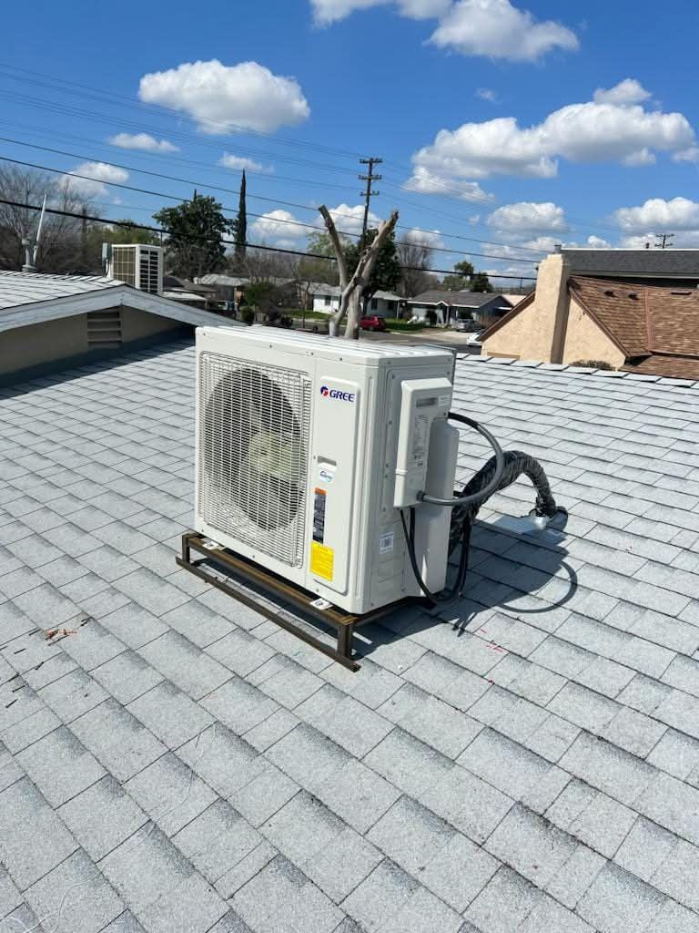A white air conditioner is sitting on top of a roof.