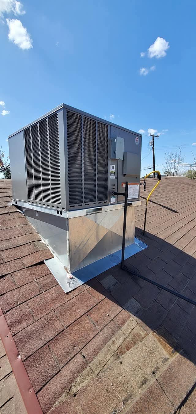 A large air conditioner is sitting on top of a brick roof.