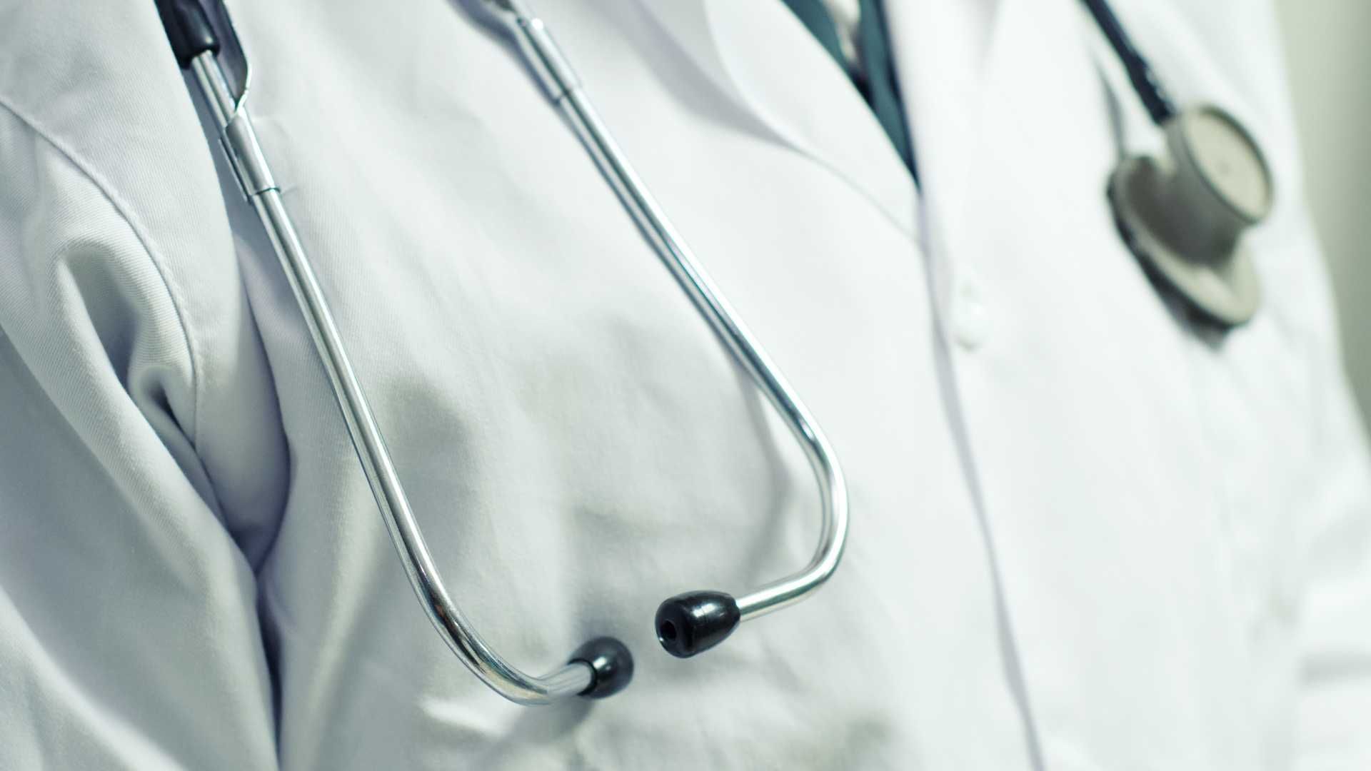 A close up of a doctor 's coat with a stethoscope around his neck.