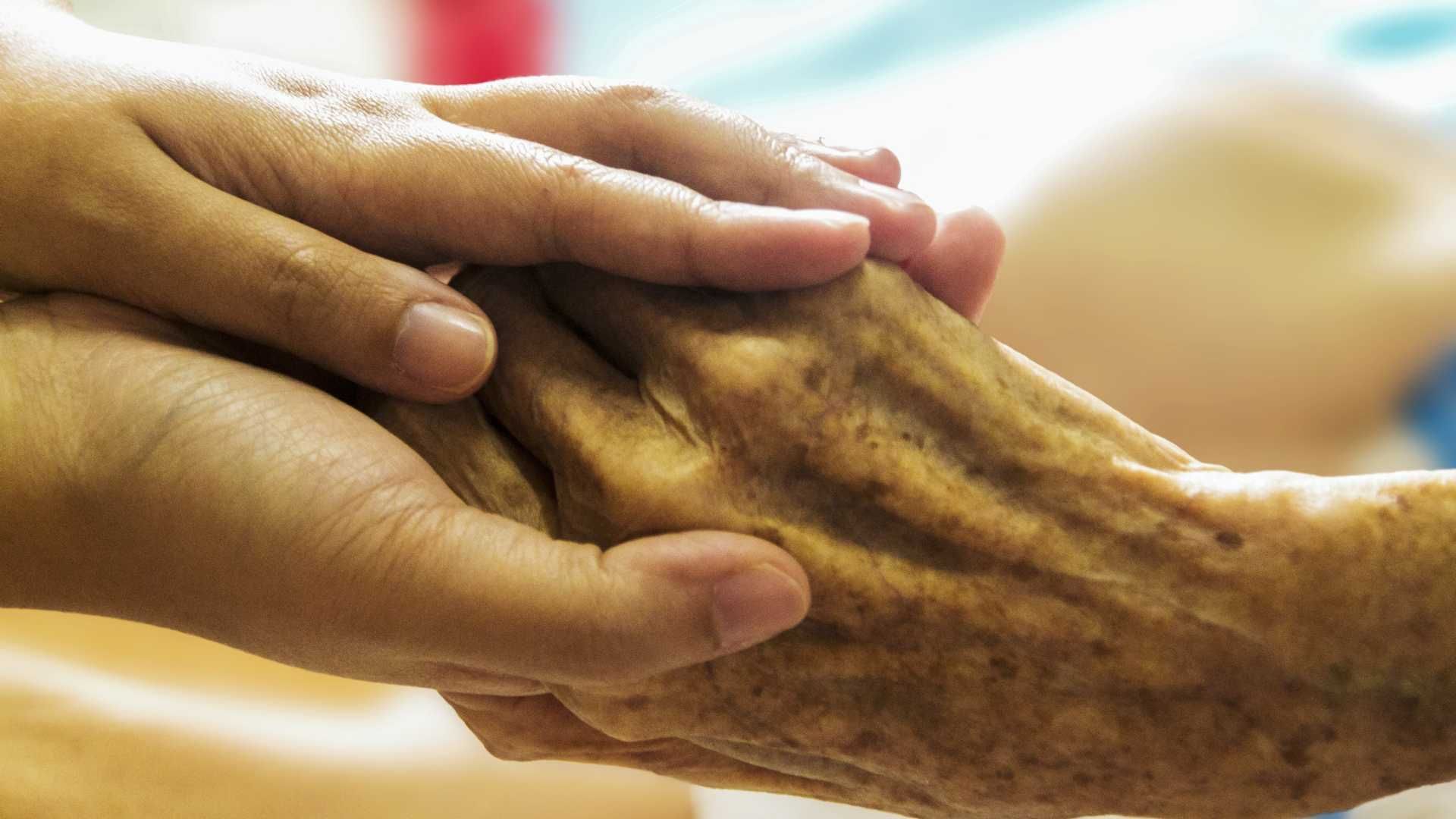 A close up of a person holding an older person 's hand.