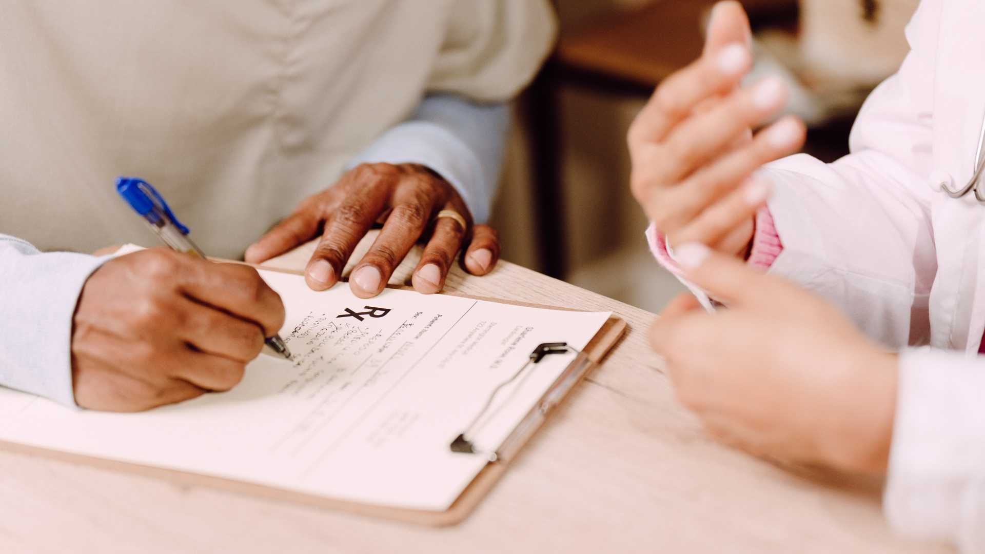 A close up of a person signing a document on a clipboard.