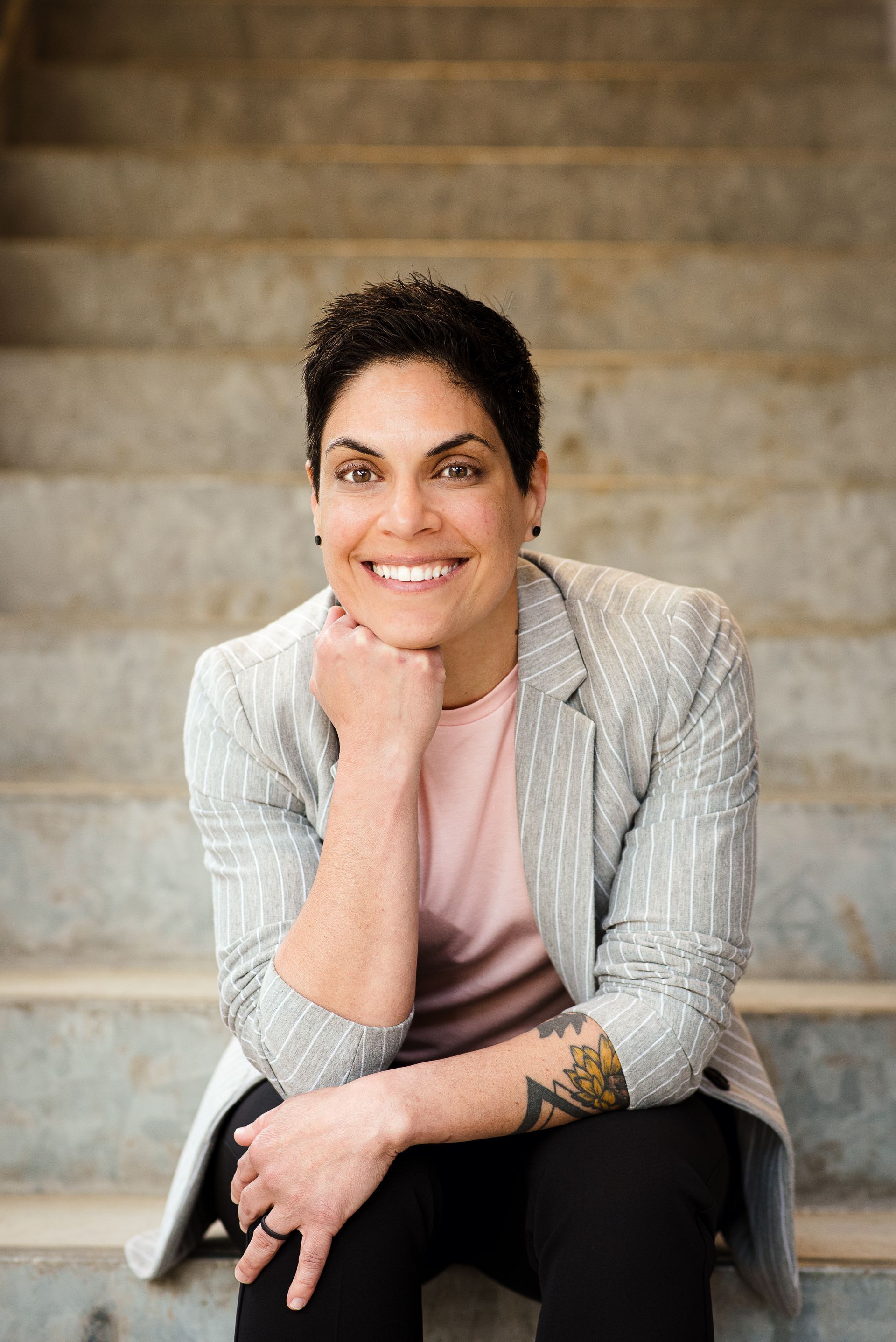 A woman is sitting on a set of stairs with her hand on her chin.