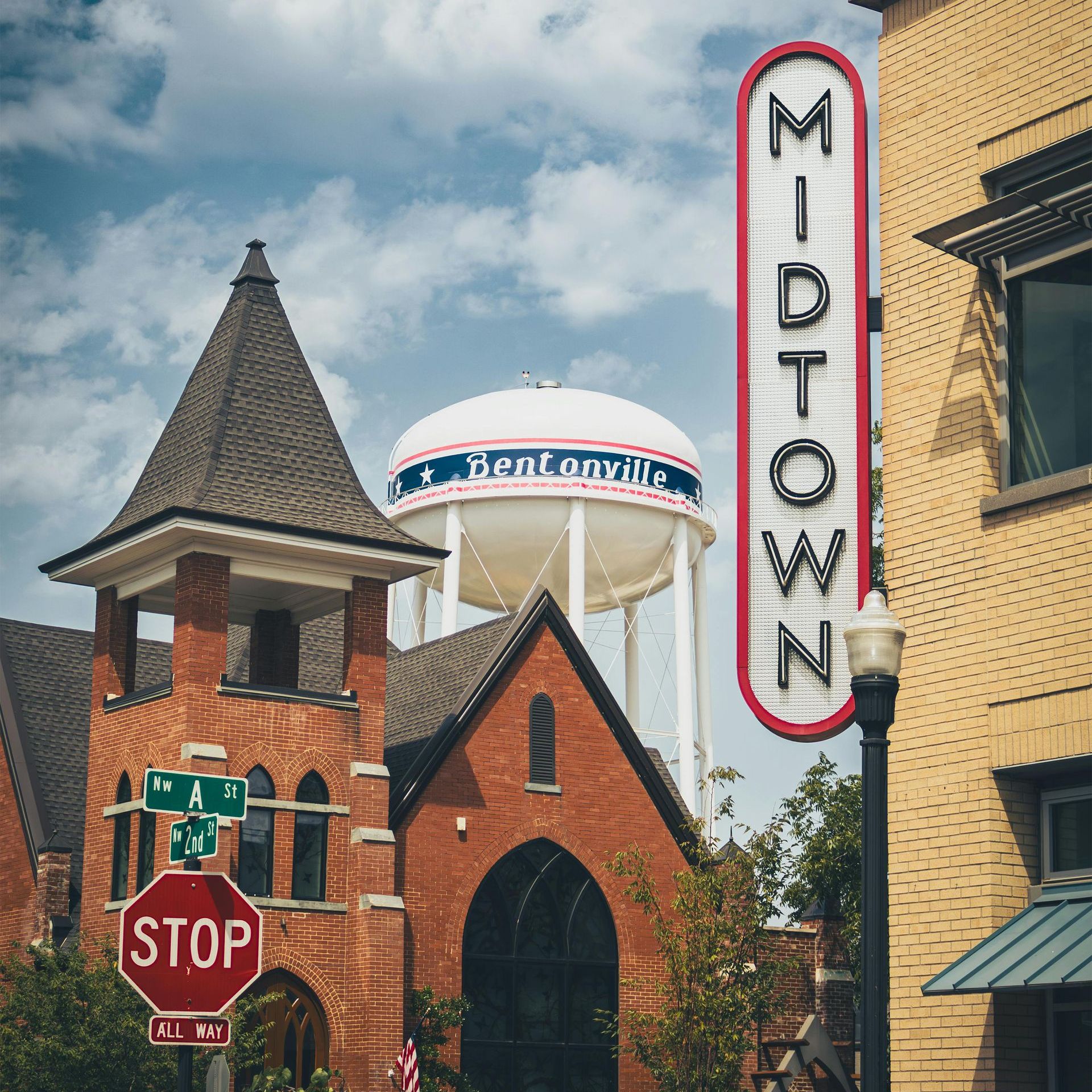 A stop sign is in front of a midtown sign