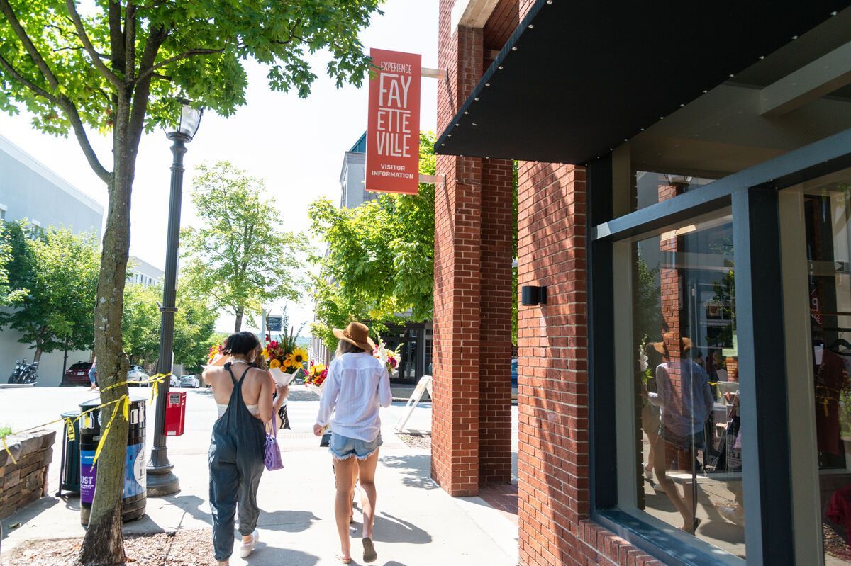 A group of people are walking down a sidewalk in front of a store.