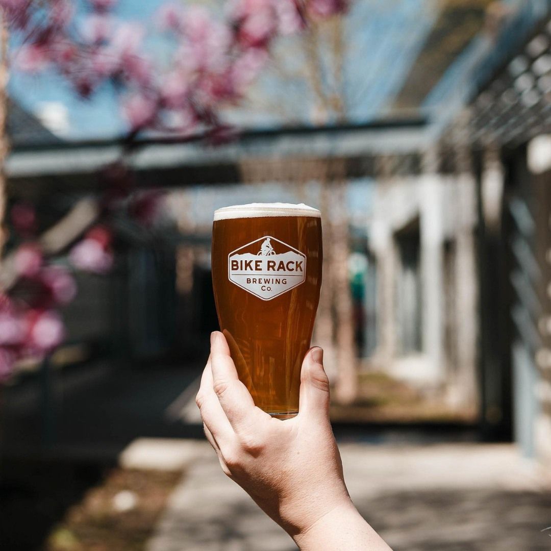 A person is holding a glass of beer that says bike rack on it