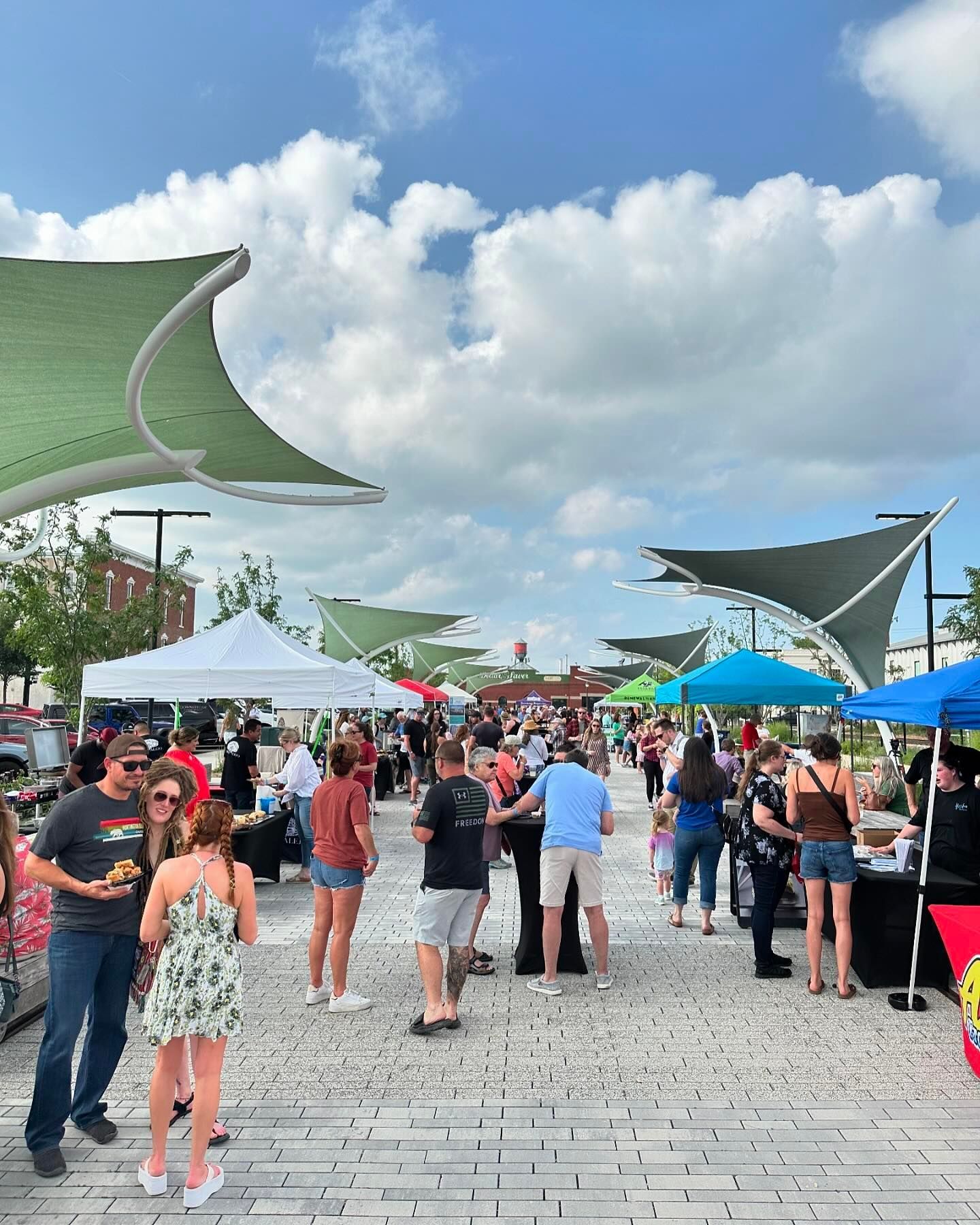 A group of people are standing under tents at a market.