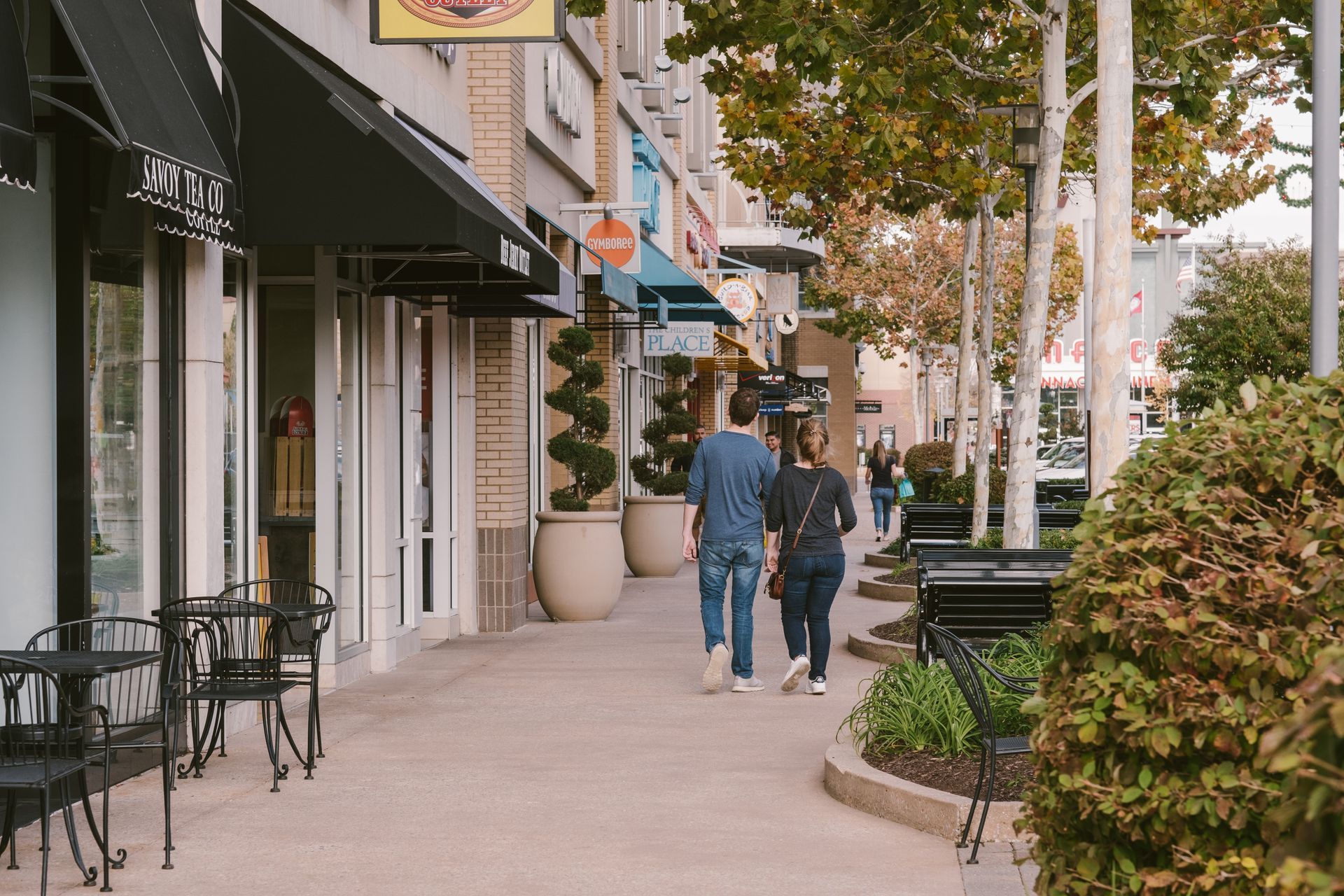 A man and a woman are walking down a sidewalk in a city.