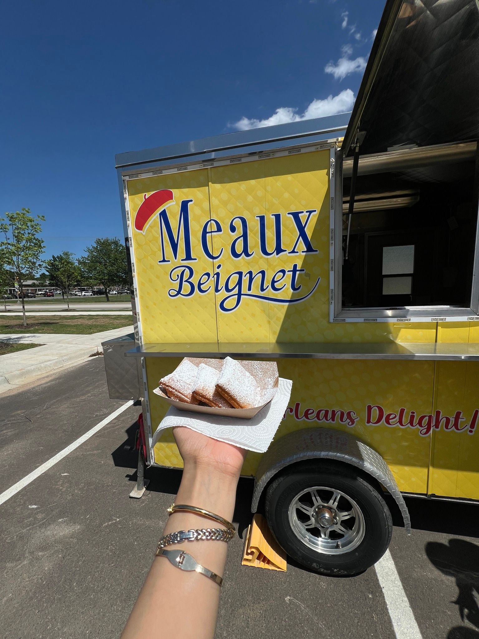 A person is holding a plate of food in front of a food truck.