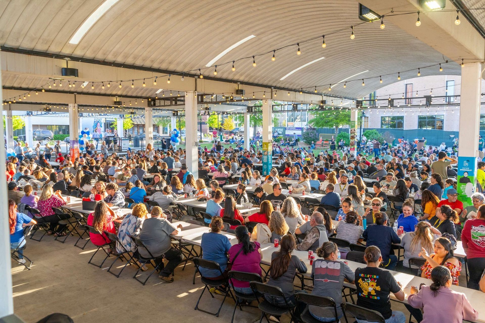 A large group of people are sitting at tables in a public area