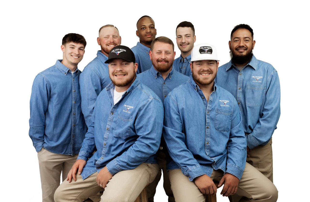 Seven people in blue shirts and khaki pants posing together against a white background.
