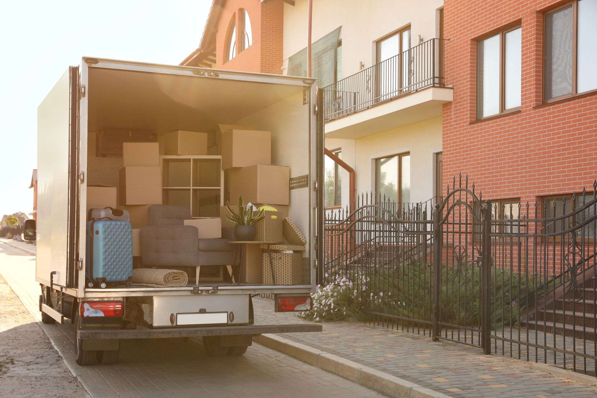 Moving truck loaded with boxes parked beside a brick apartment building