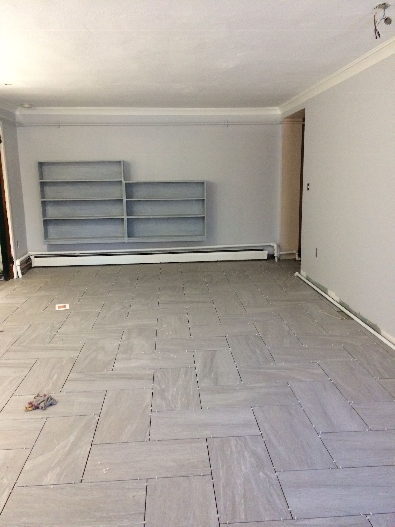 A large empty room with a tiled floor and shelves.