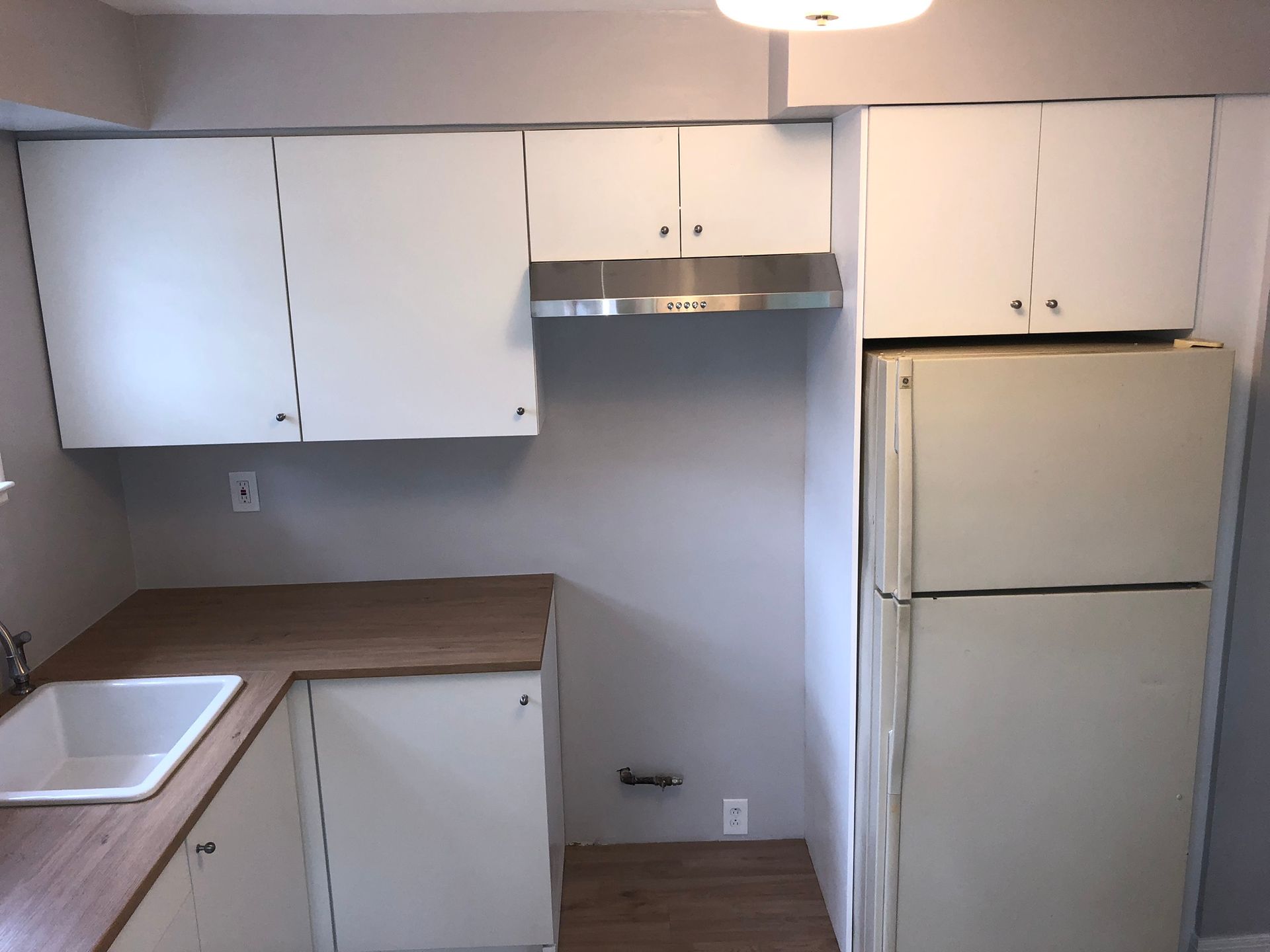 A kitchen with white cabinets and a white refrigerator
