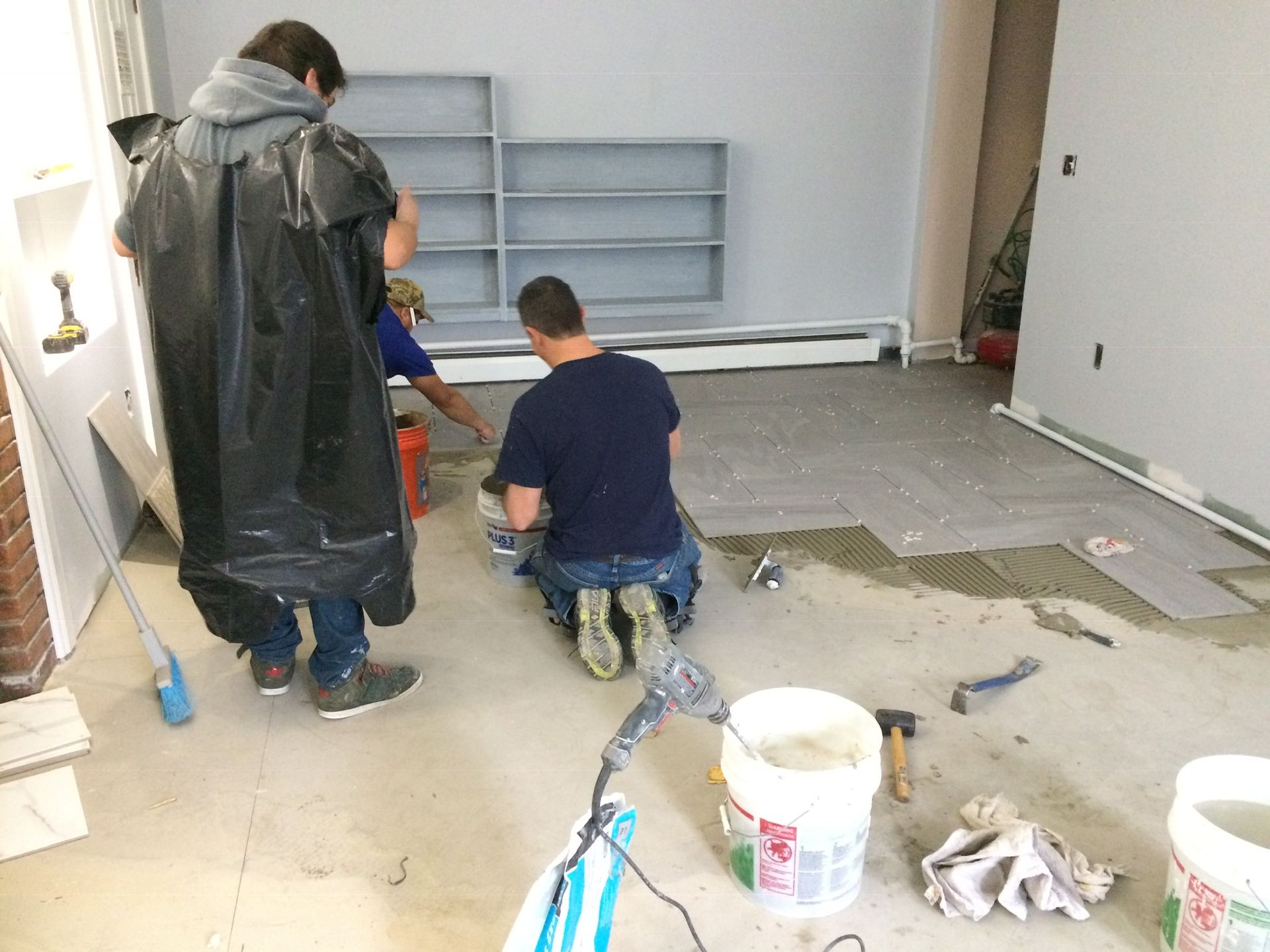 A group of men are working on a floor in a room.