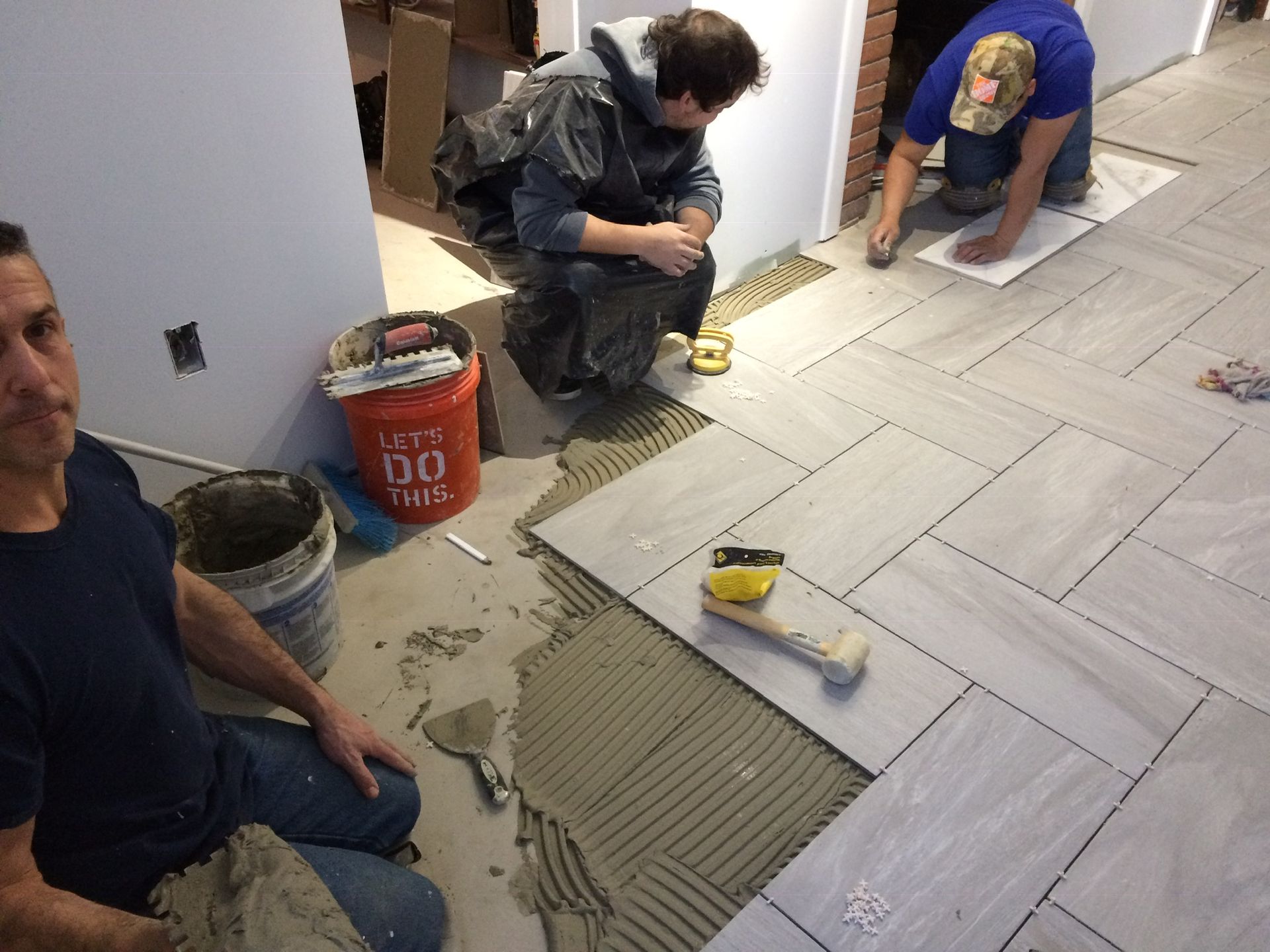 A group of men are working on a tile floor.
