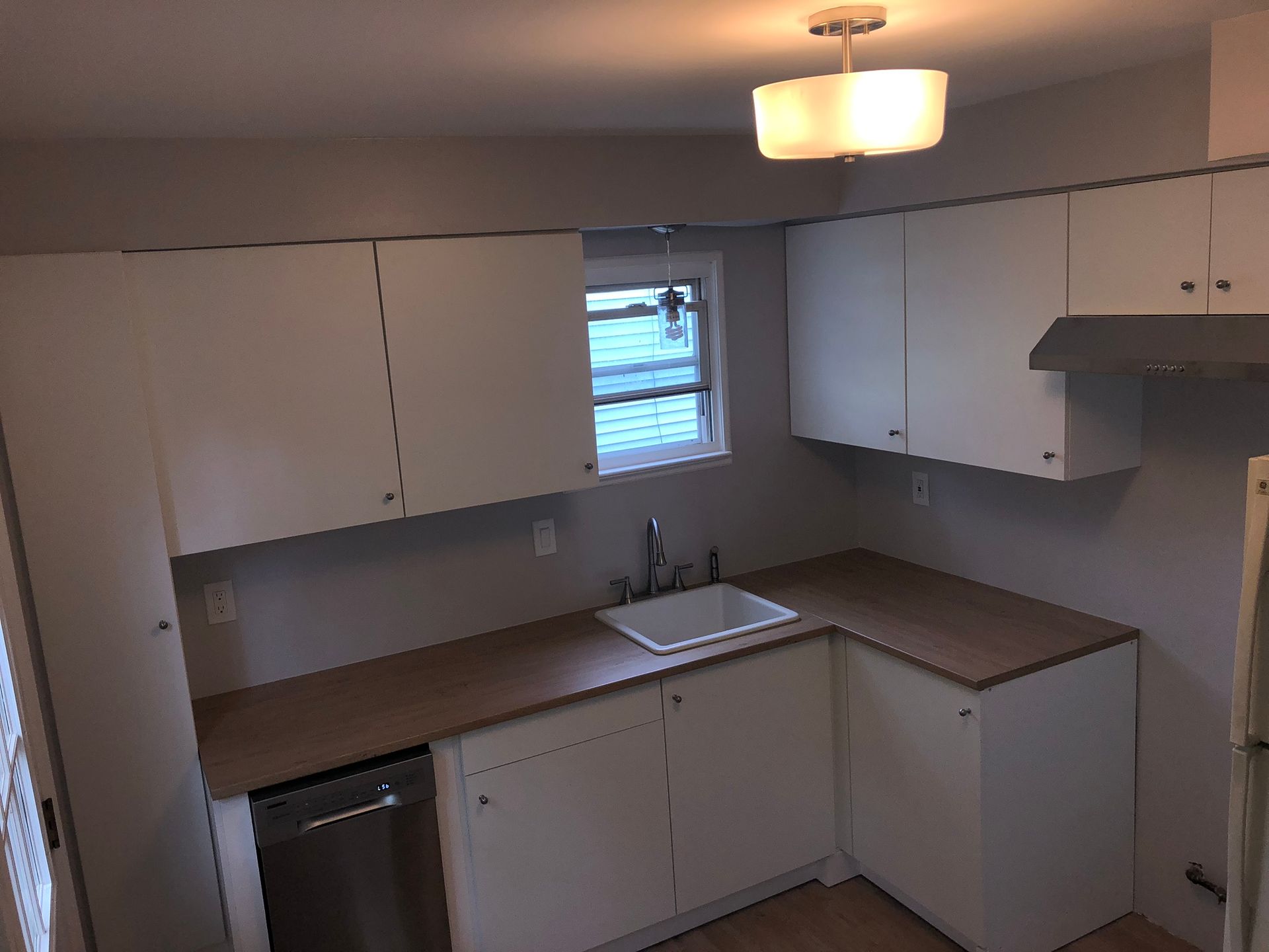 An empty kitchen with white cabinets and a sink