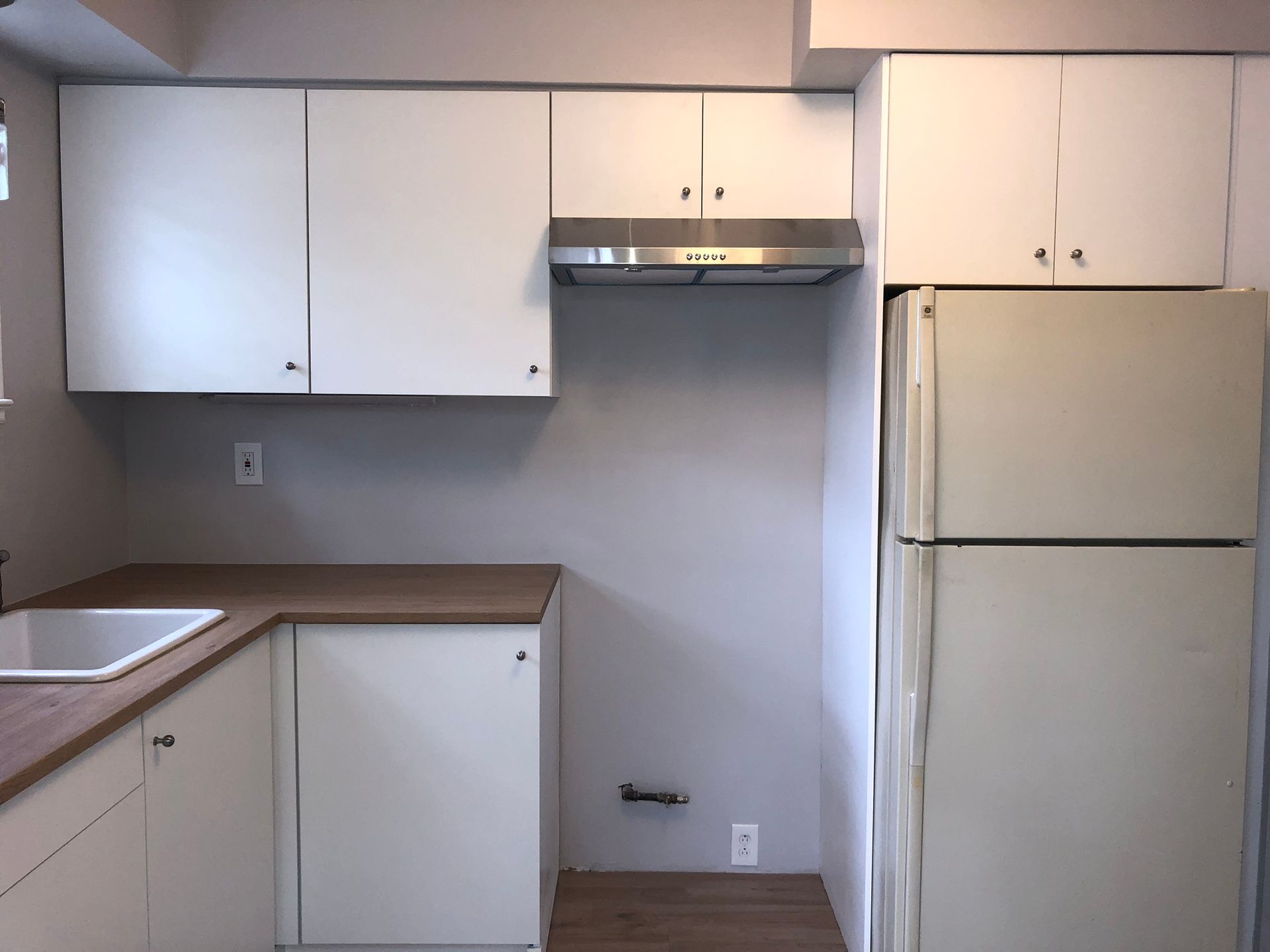 A kitchen with white cabinets and a white refrigerator