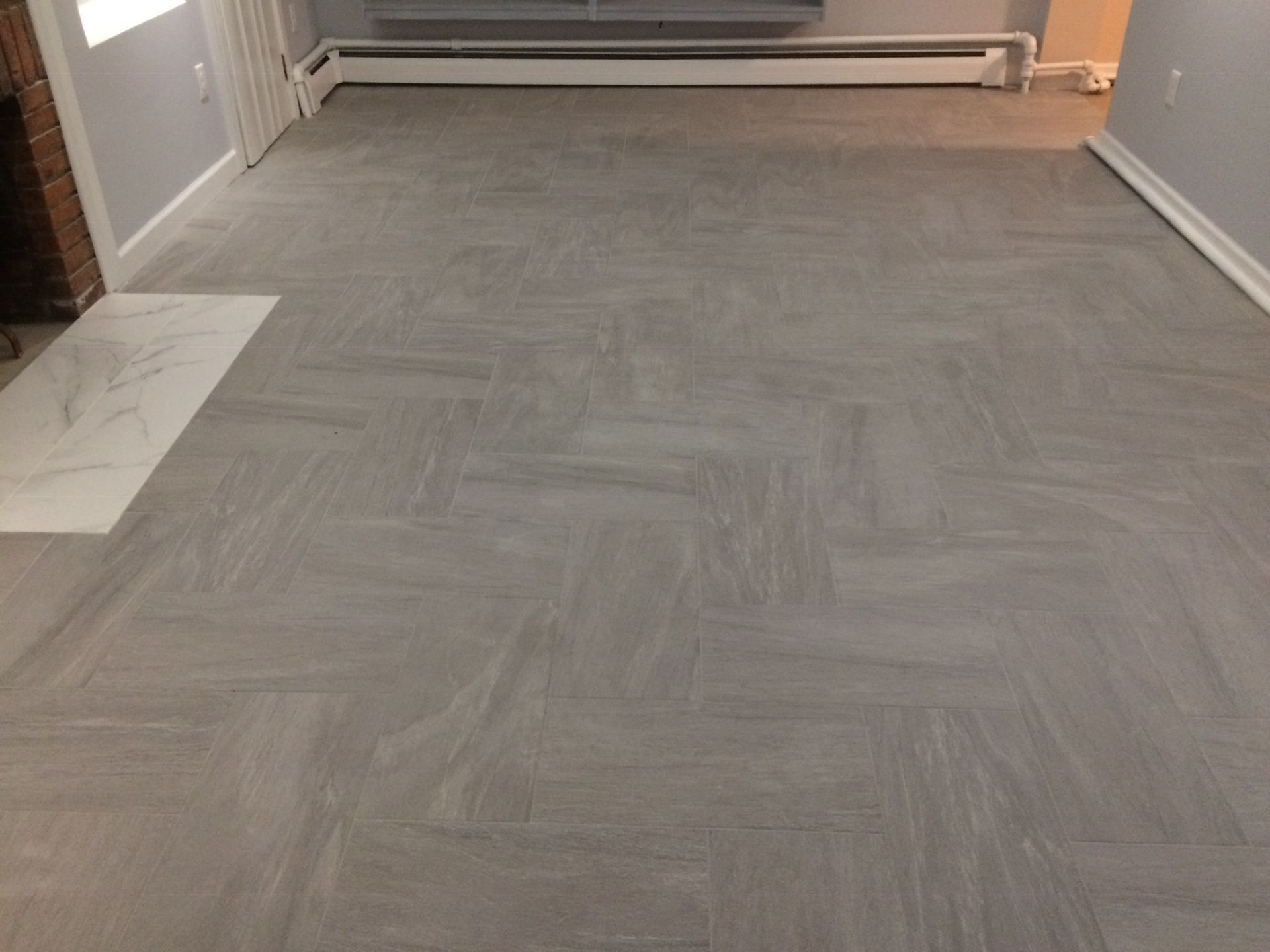 A living room with a herringbone floor and a fireplace.