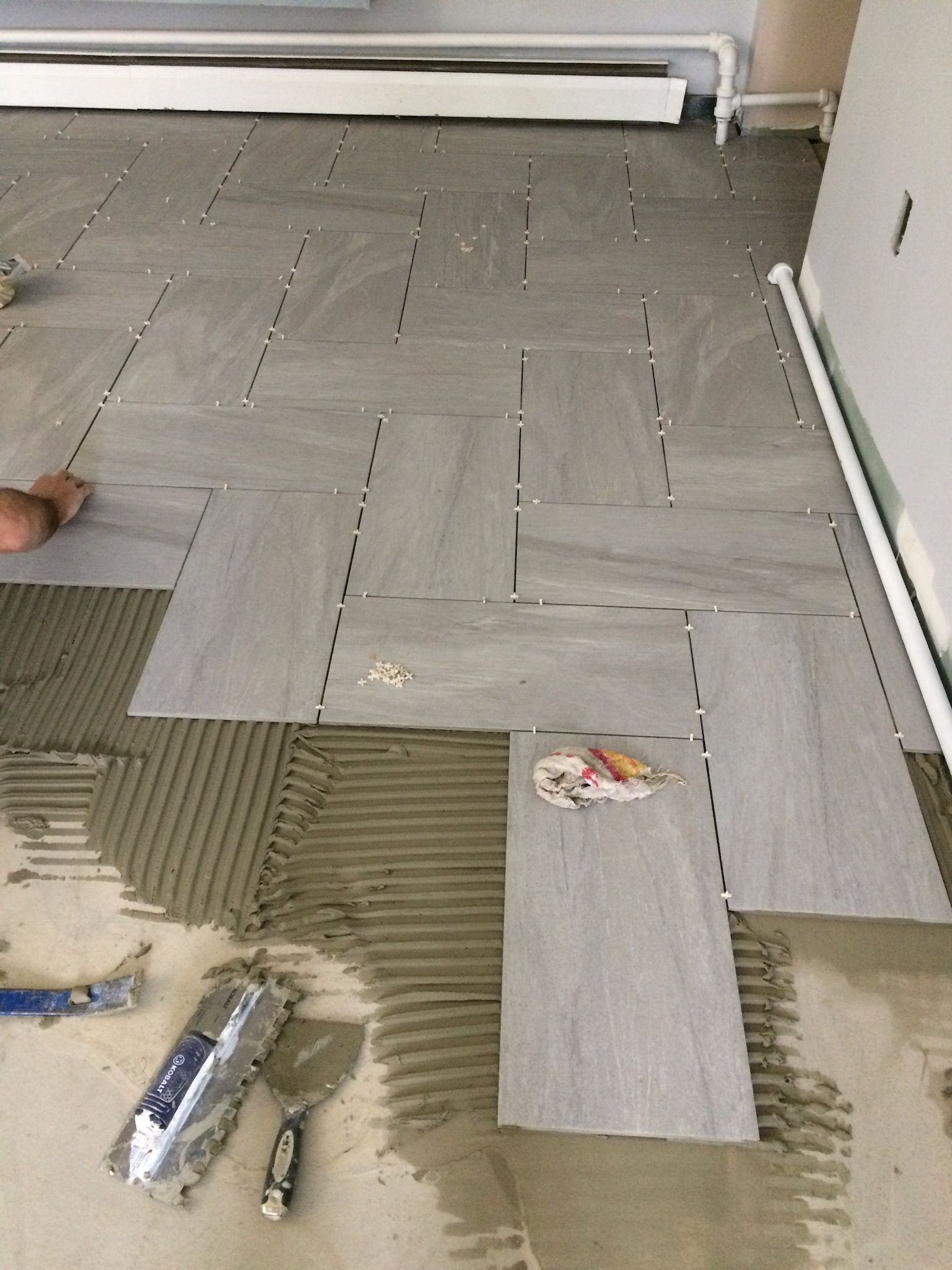 A person is laying tiles on the floor in a room.
