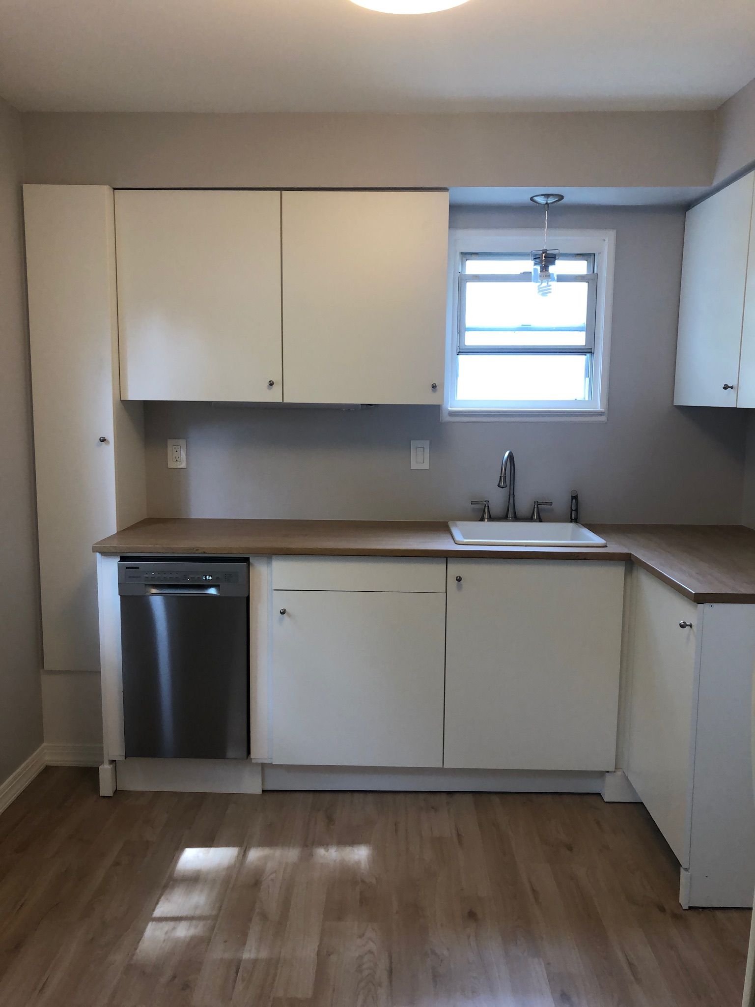 A kitchen with white cabinets and a stainless steel dishwasher