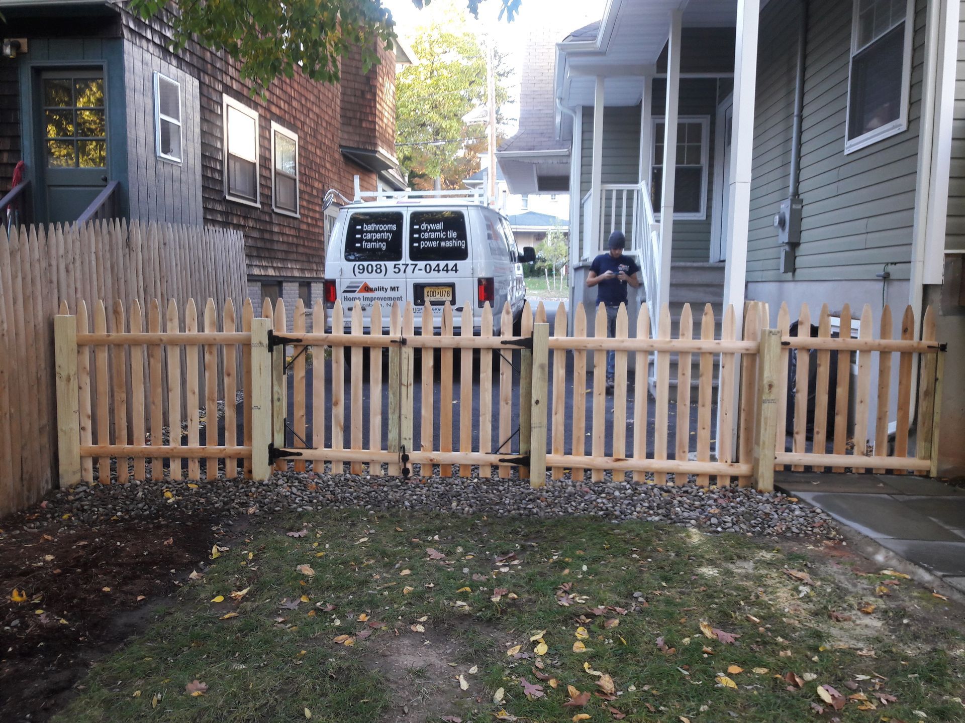 A wooden picket fence is in front of a house