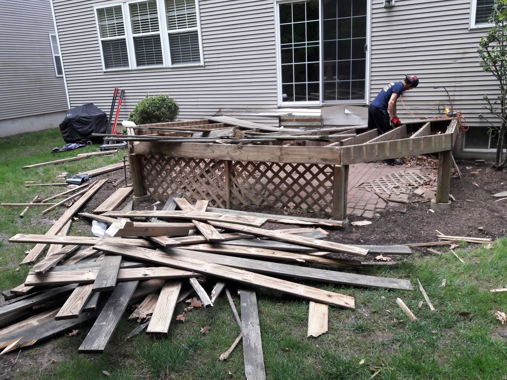 A man is working on a wooden deck in a backyard.