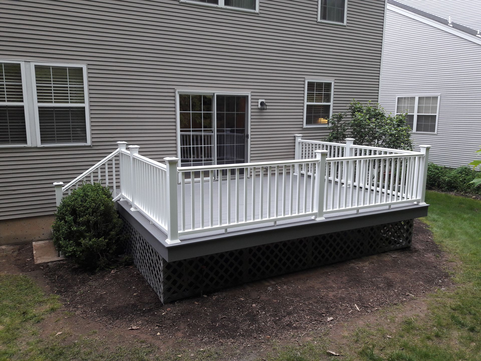 A white deck with a white railing is in front of a house.