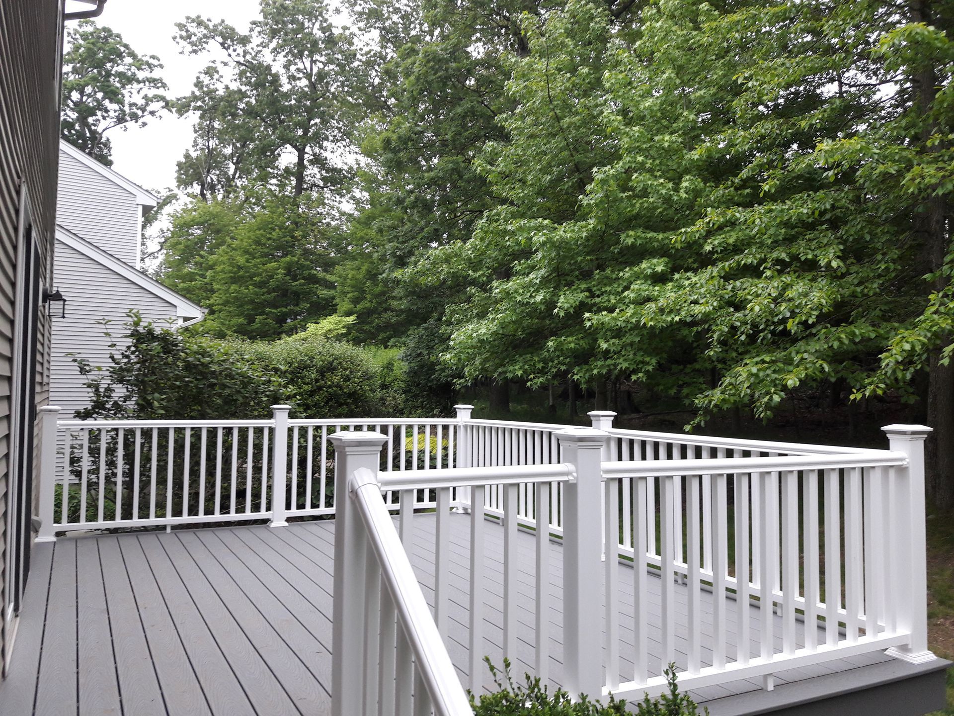 A deck with a white railing and trees in the background