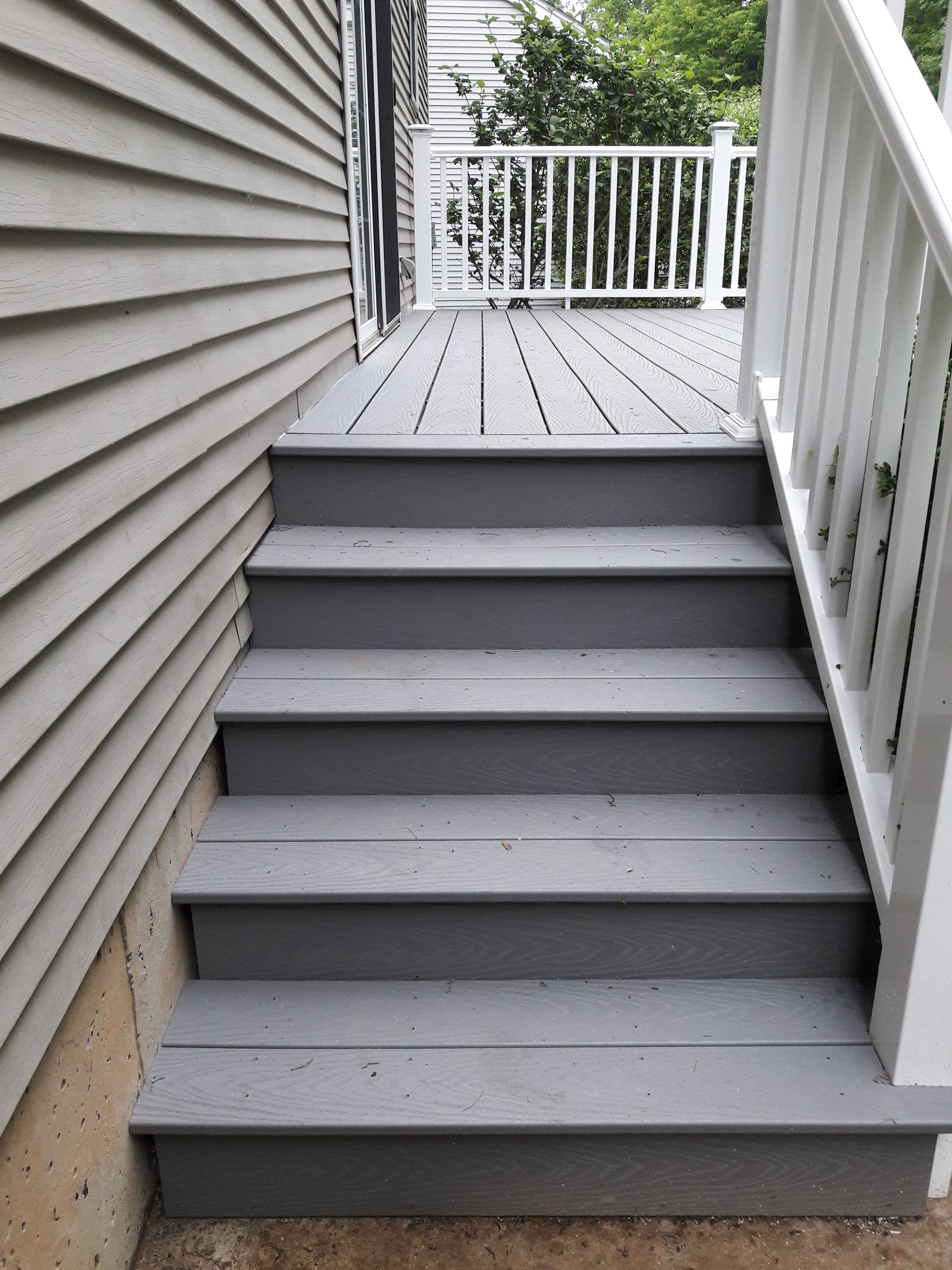 A set of stairs leading up to a deck with a white railing.
